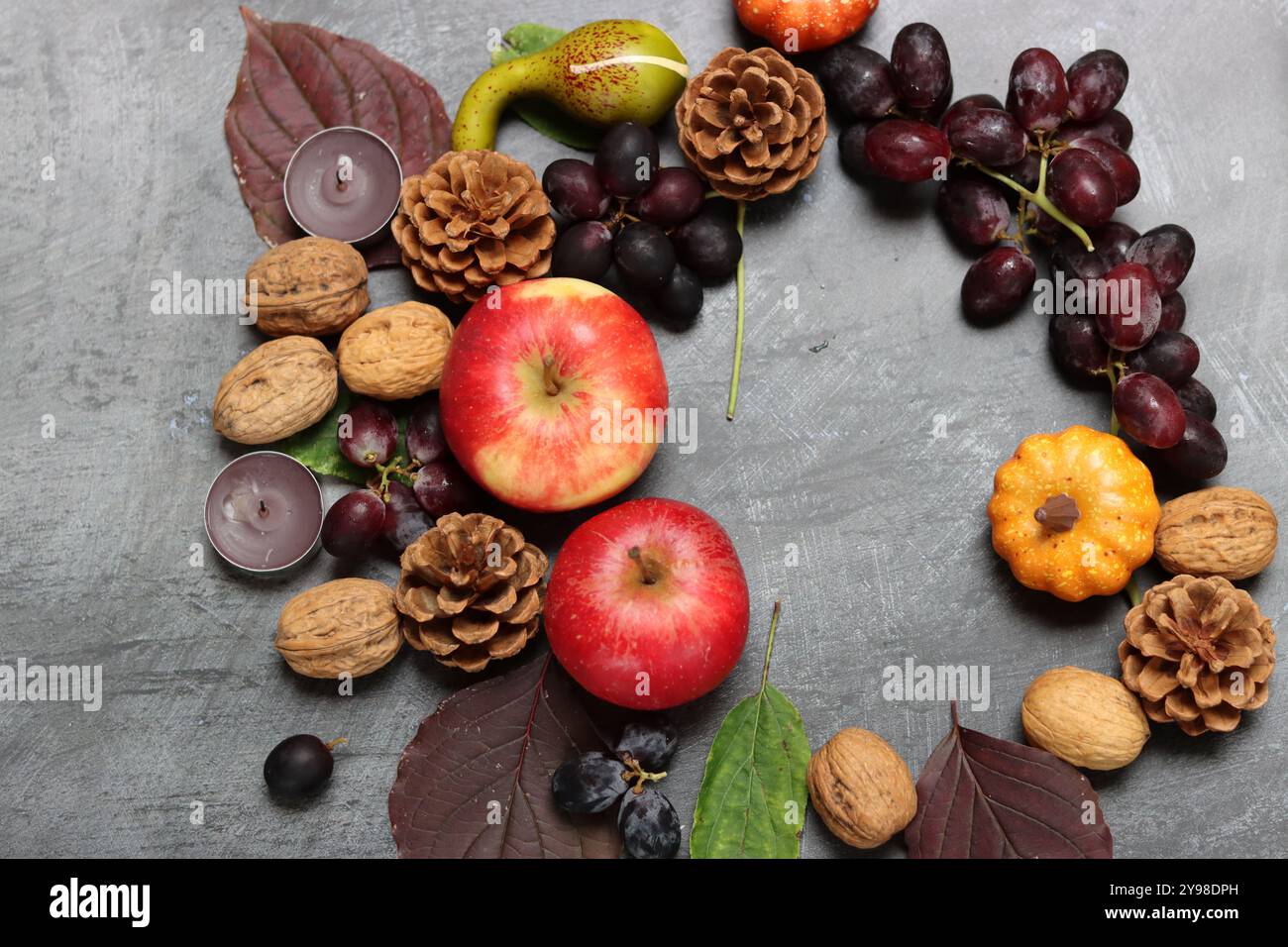 Autumn composition with apples, walnuts and leaves on grey background Stock Photo