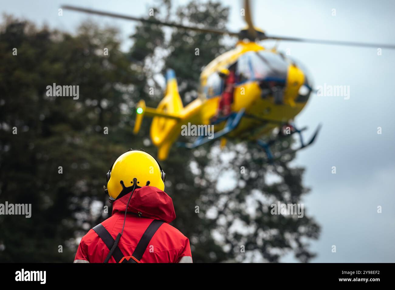 Rear view of paramedic against landing helicopter of emergency medical service. Themes rescue, help and hope. Stock Photo