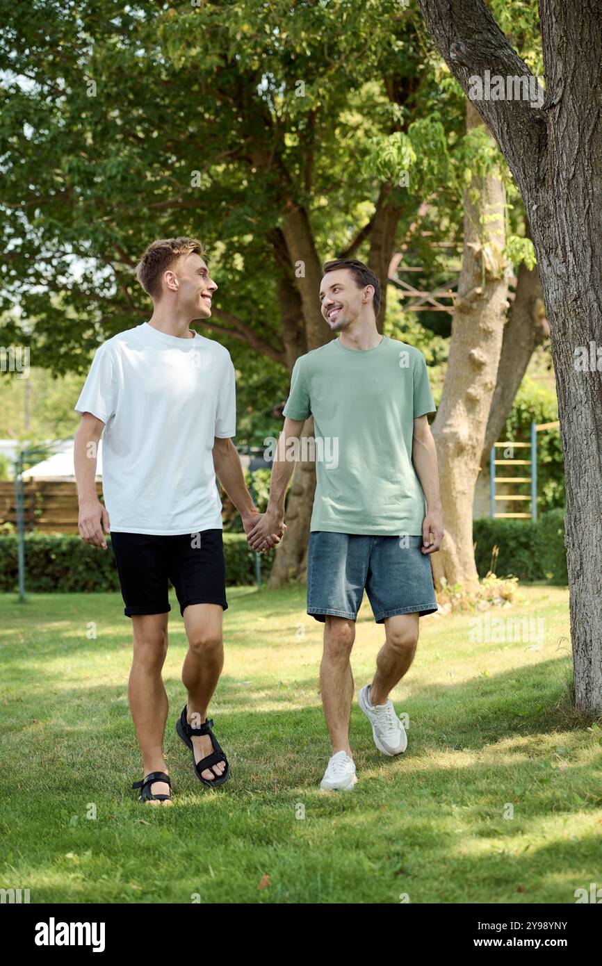 A joyful couple strolls hand in hand through a green park, sharing ...
