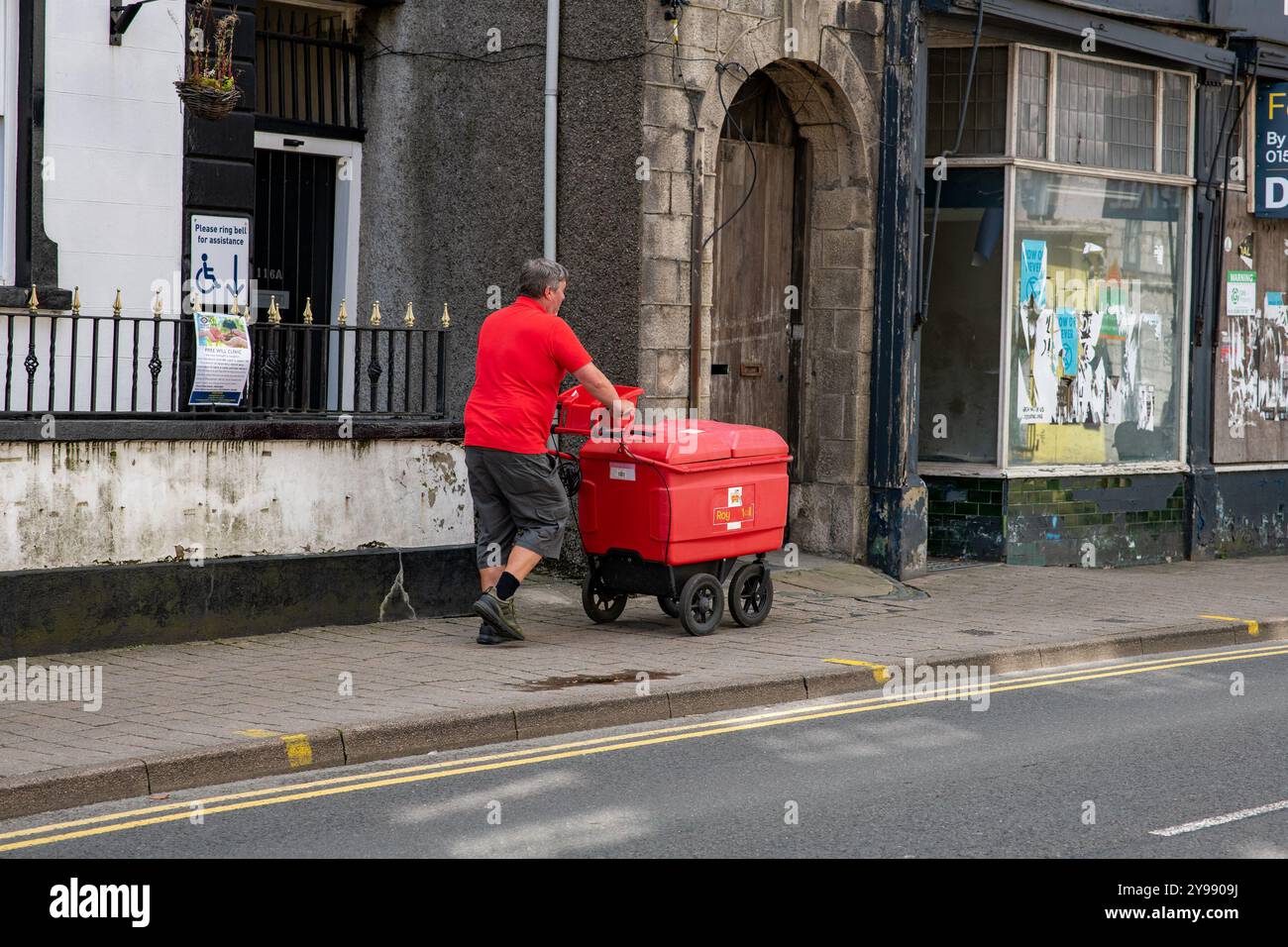 A Royal Mail postman delivering post, Kendal, Cumbria, UK Stock Photo