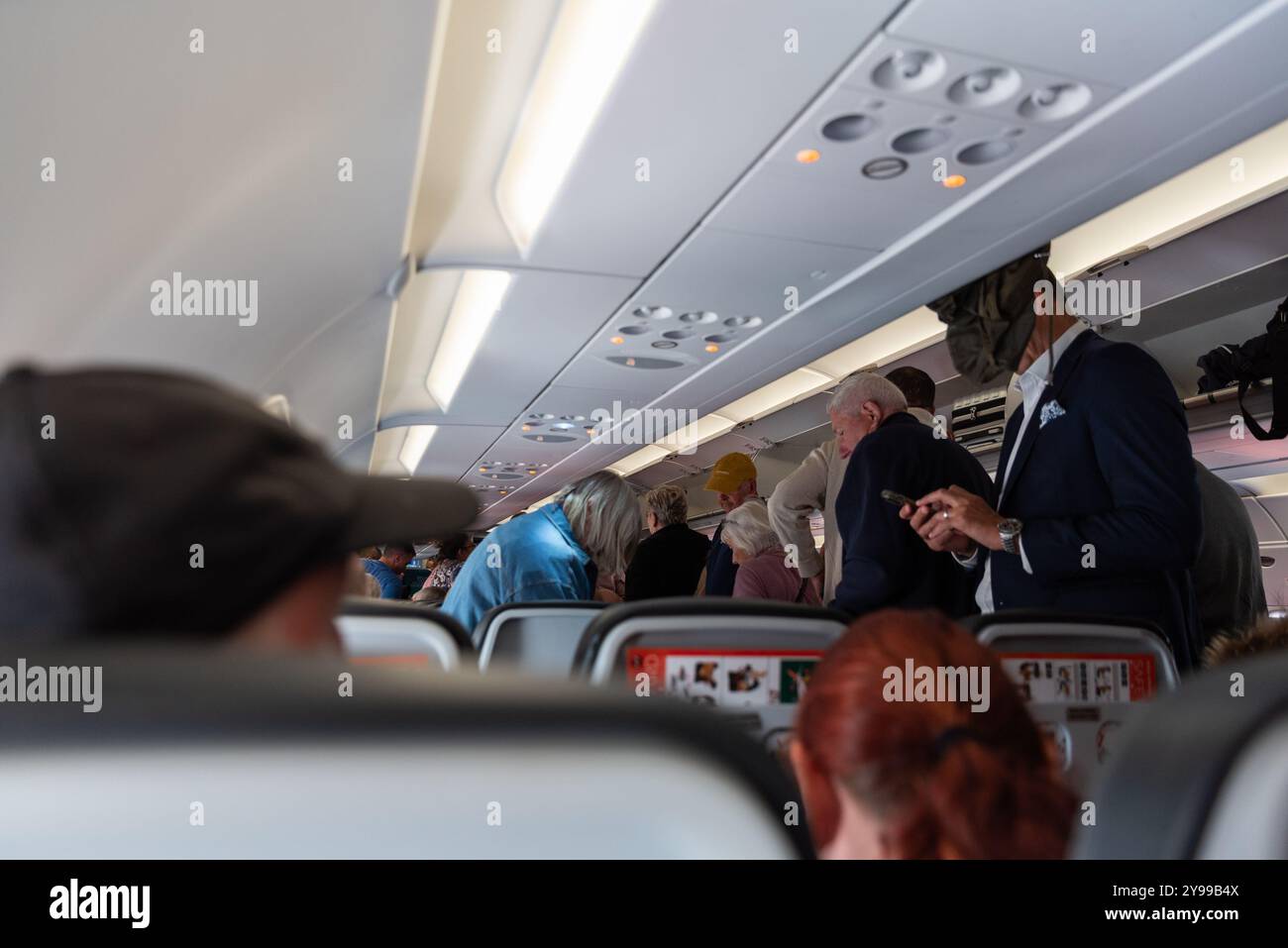 Passengers standing up as soon as an easyJet airliner stops at London Gatwick airport, UK. Impatient travellers Stock Photo