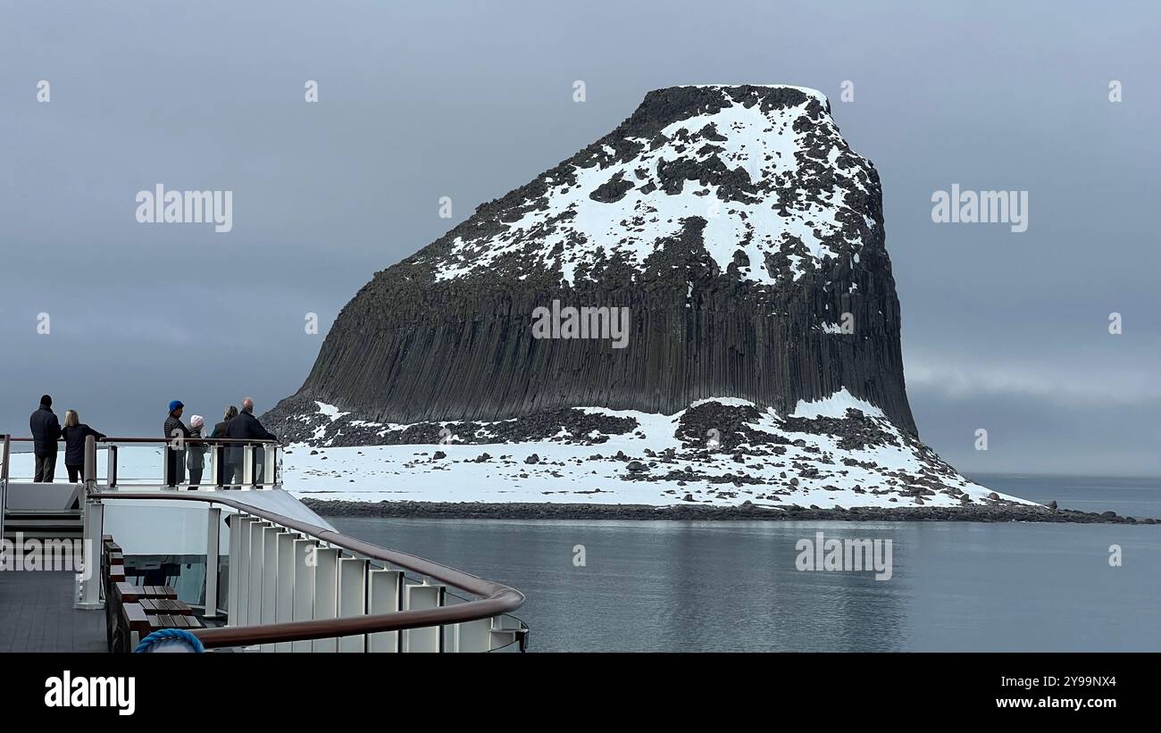 Passengers aboard the Lindblad Nat Geo Endurance take in the dramatic view of Edinburgh Rock in Antarctica, as the ship approaches - Smartphone Captured Stock Image