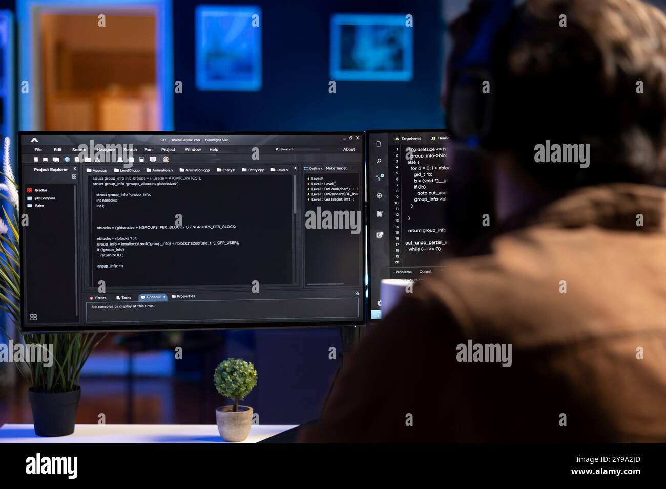 Man doing software quality assurance, reading source code on computer screen before implementing it. Developer inspecting coding on desktop PC, looking to fix potential issues Stock Photo