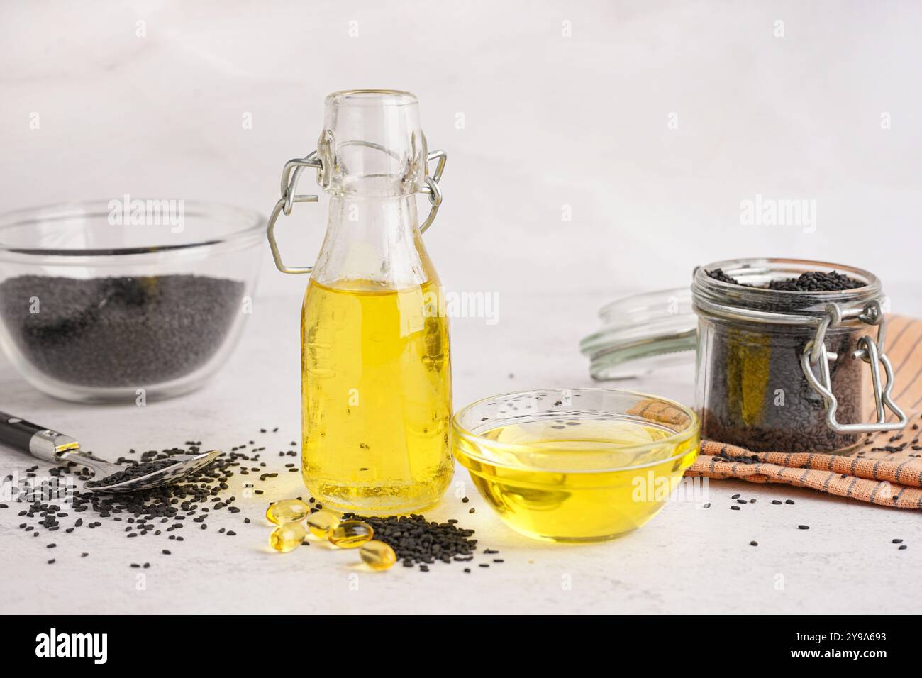 Bottle and bowl of oil with sesame seeds on white background Stock ...