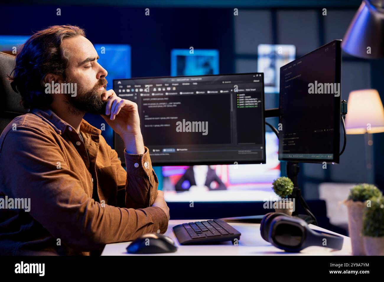 Pensive man doing software quality assurance, carefully analyzing source code on computer screen. Developer thinking of solutions after finding errors while inspecting coding on desktop PC Stock Photo
