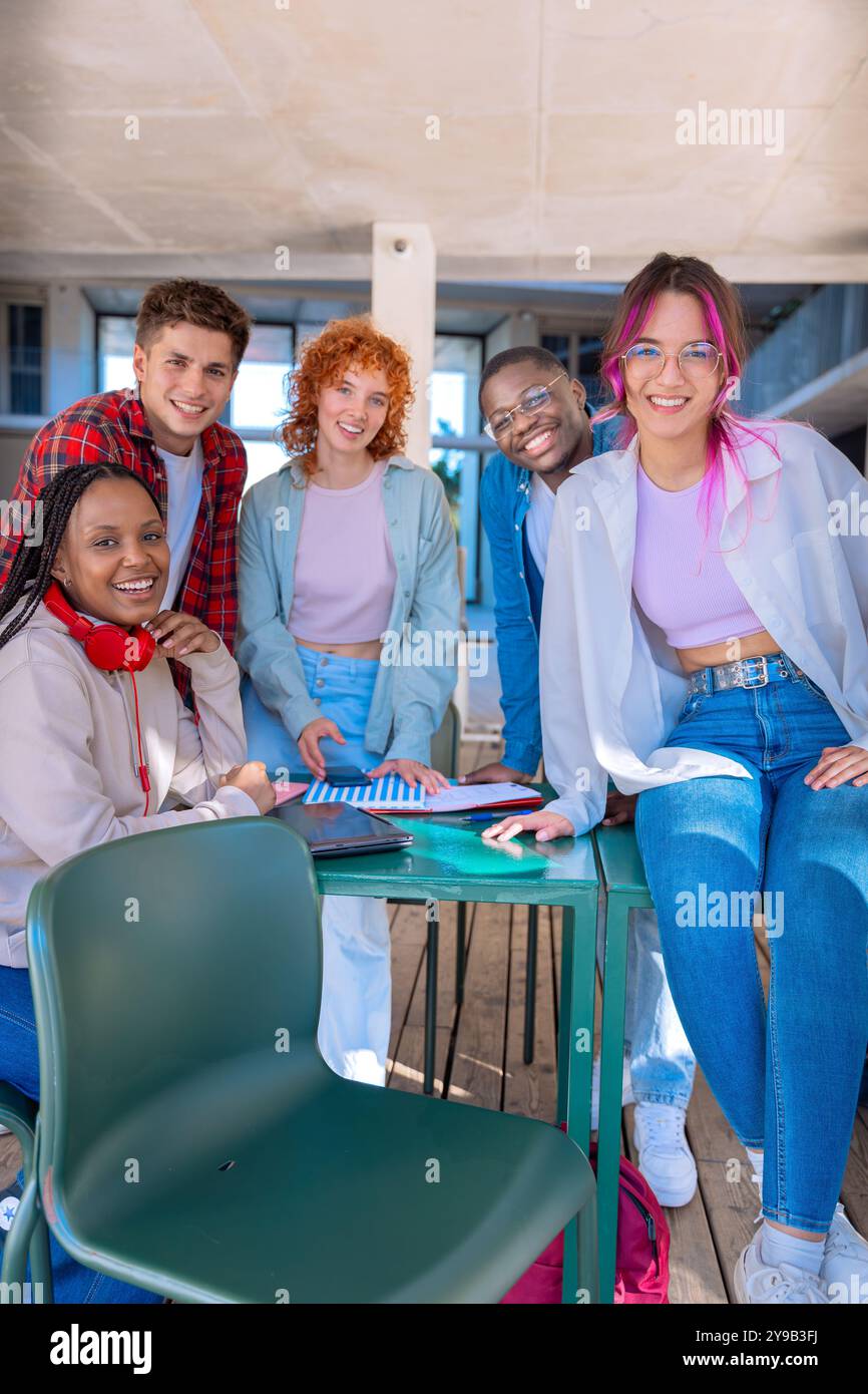 Happy diverse group of students studying in the library looking at camera Stock Photo