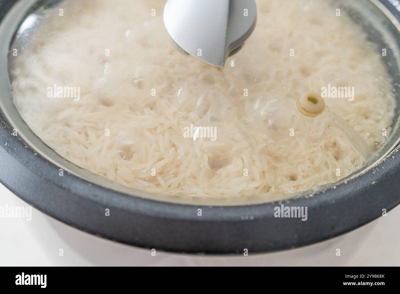 Electric rice cooker appliance boiling white rice Stock Photo - Alamy