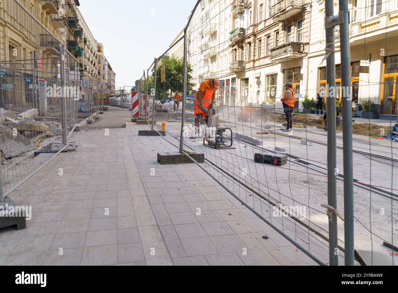 Poznan, Poland - June 19, 2023: Amidst the bustle of a vibrant city, construction workers are actively repairing the street, generating dust and noise Stock Photo