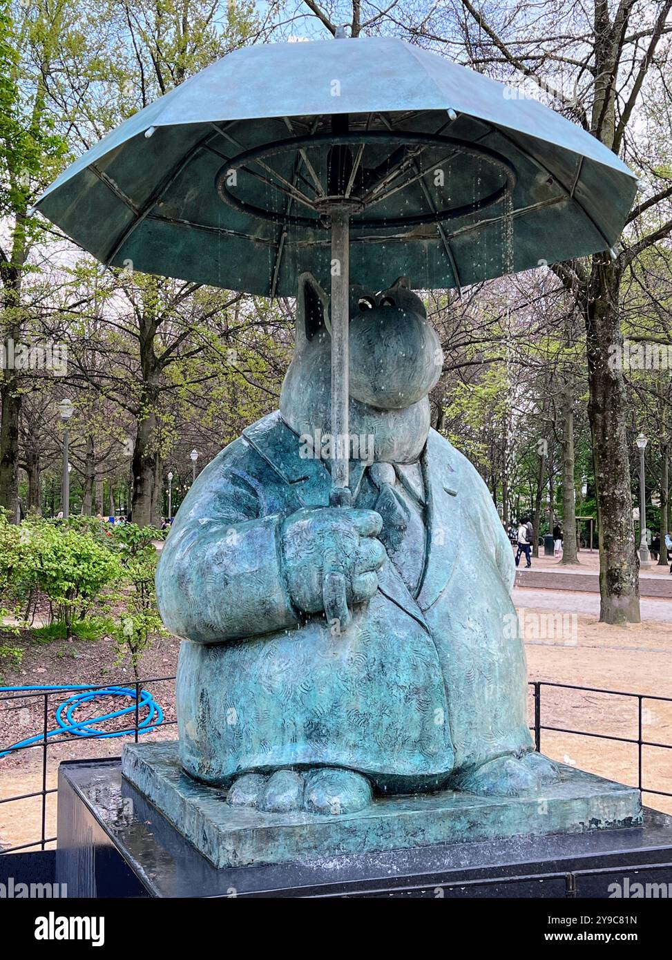 Statue of famous Le Chat cat in the Parc de Bruxelles in Brussels, by Philippe Geluck, holding an umbrella, capturing quirky and playful city scene - Smartphone Captured Stock Image