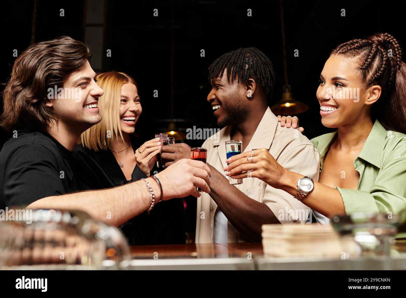 Diverse group of young professionals share laughter and drinks at a ...