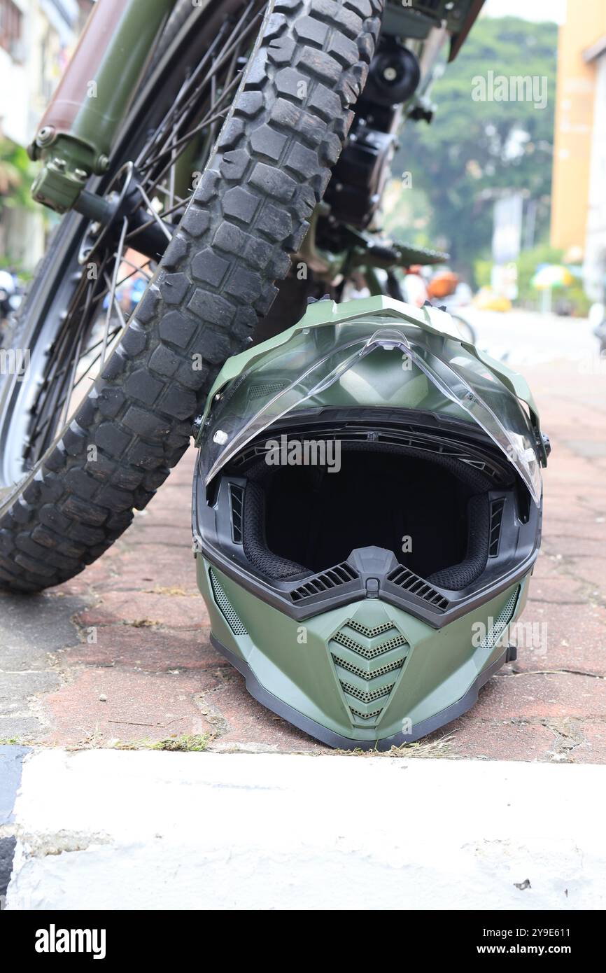 Close-up of a military motorcycle and helmet on a paved surface, highlighting rugged design and combat readiness. Stock Photo