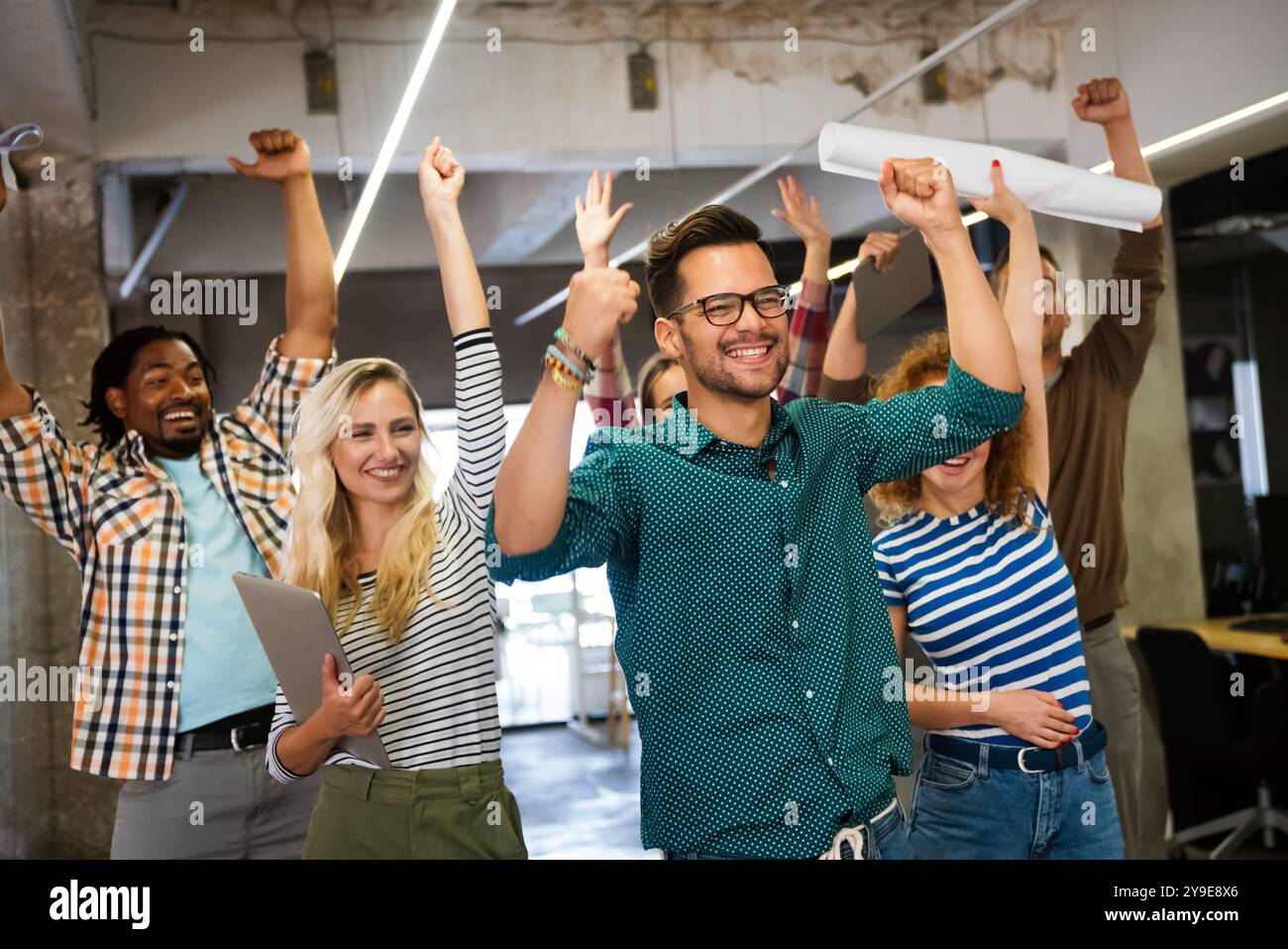 Happy young successful business team celebrating a triumph with arms up ...