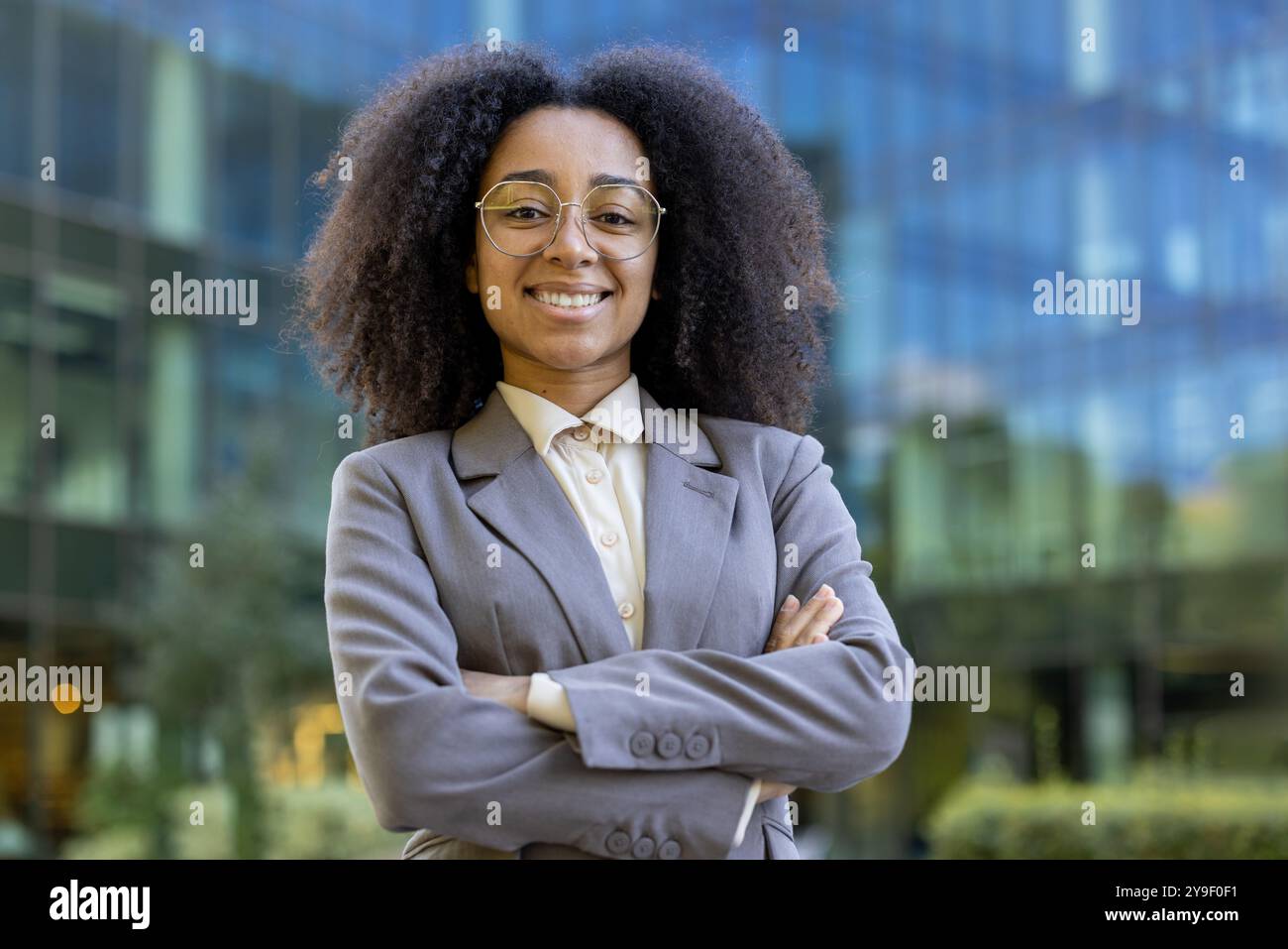 Confident African American business woman in a suit stands with crossed ...