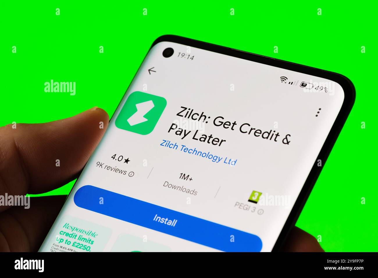 A smartphone screen displaying the Zilch app installation page with a vibrant green background. The app offers a Get Credit & Pay Later service. Staff Stock Photo