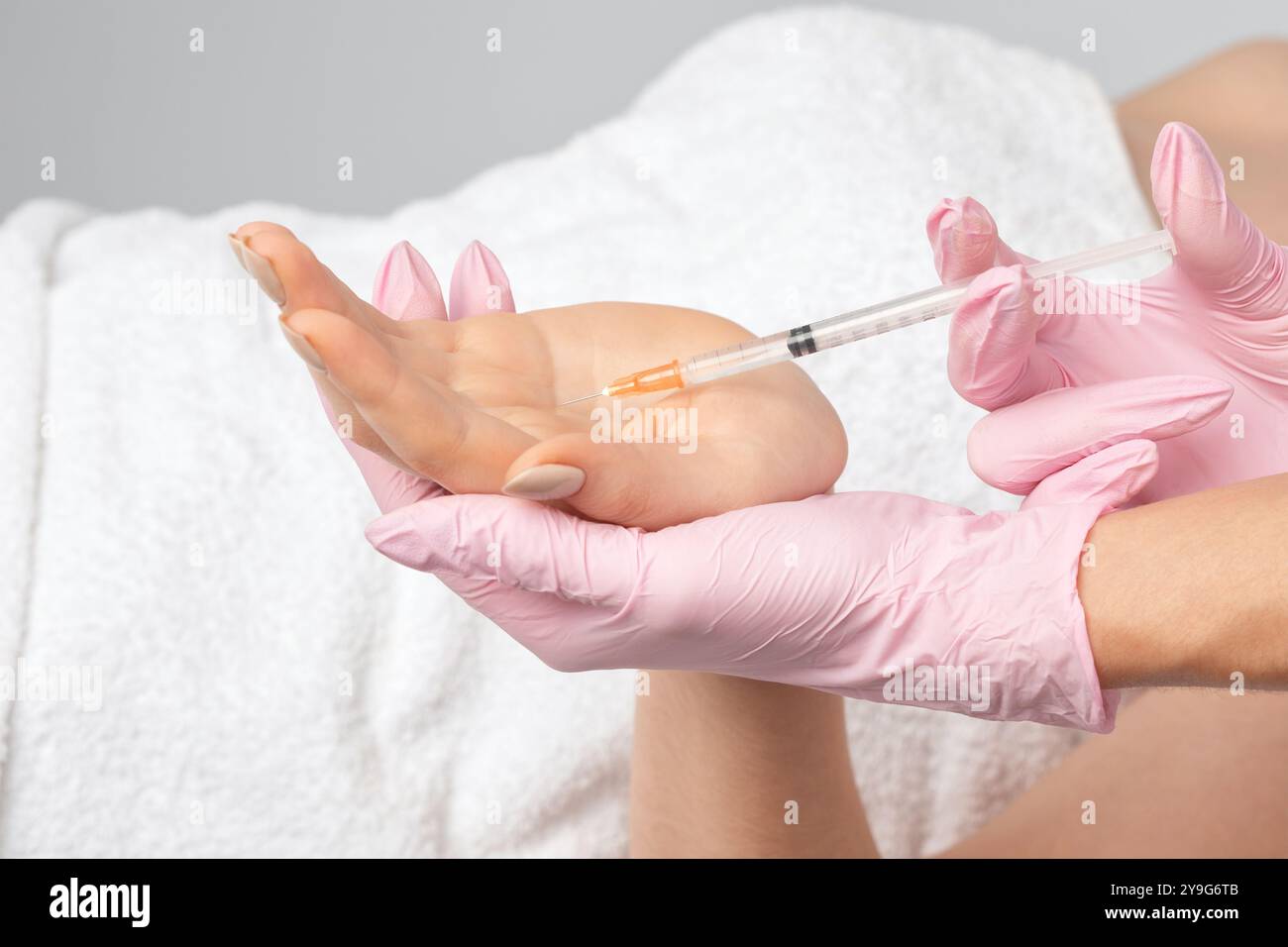 The cosmetologist makes injections of botulinum toxin on the palms of a ...