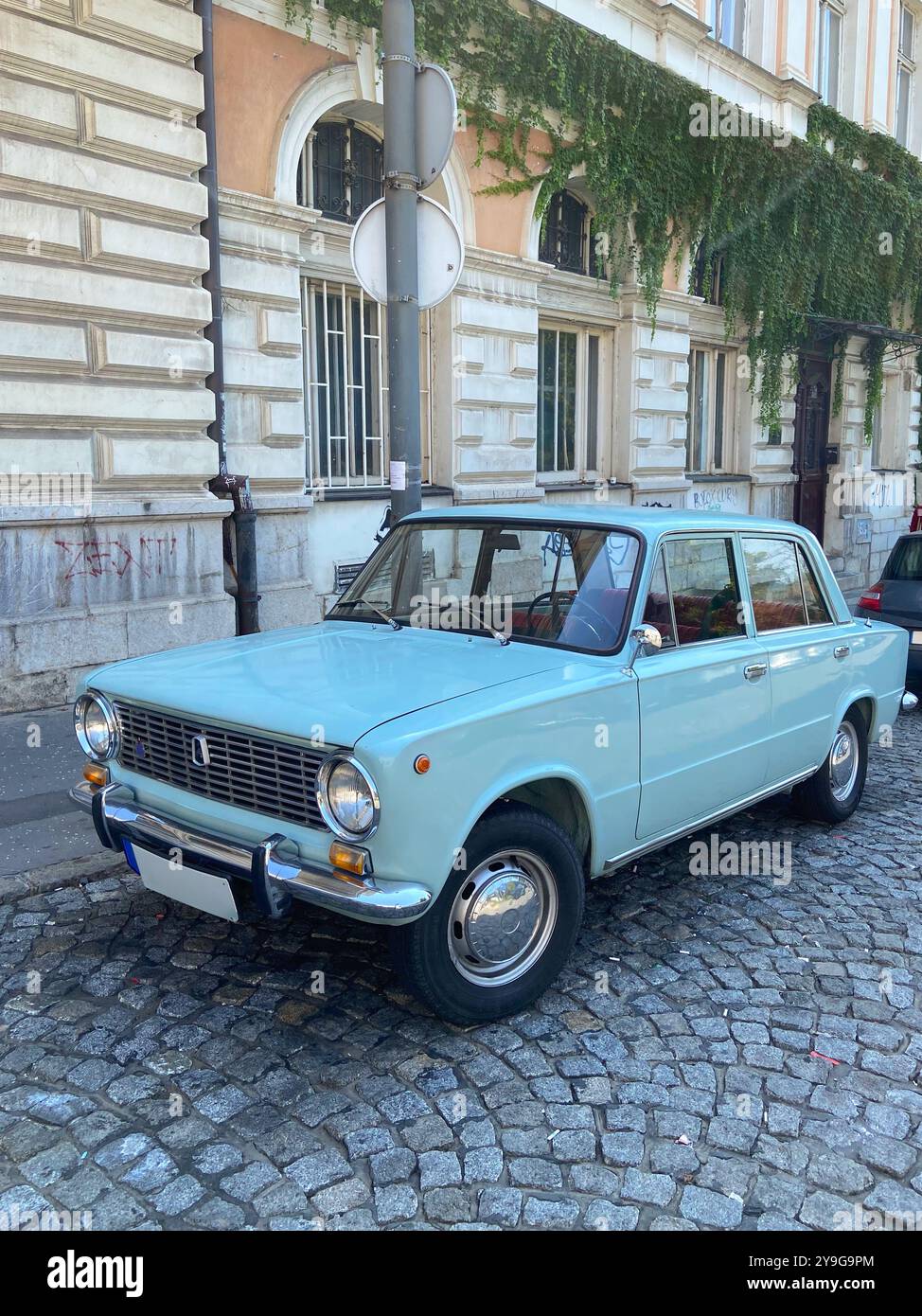 Vintage car is parked on a cobblestone street in front of a historic ...