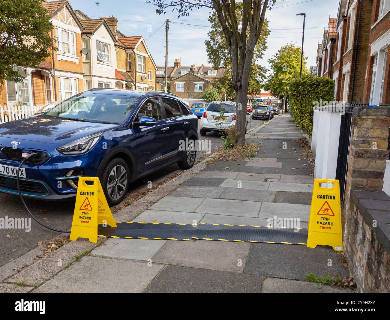 Kia electric car charging on a residential street from house using pavement cable protectors for the EV charging cable, London, UK Stock Photo