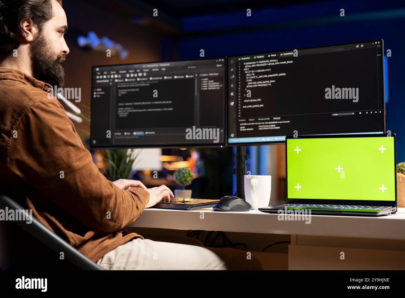 IT specialist working from home using green screen laptop, testing and deploying programs and systems. Programmer checking code displayed on computer monitors using mockup notebook Stock Photo