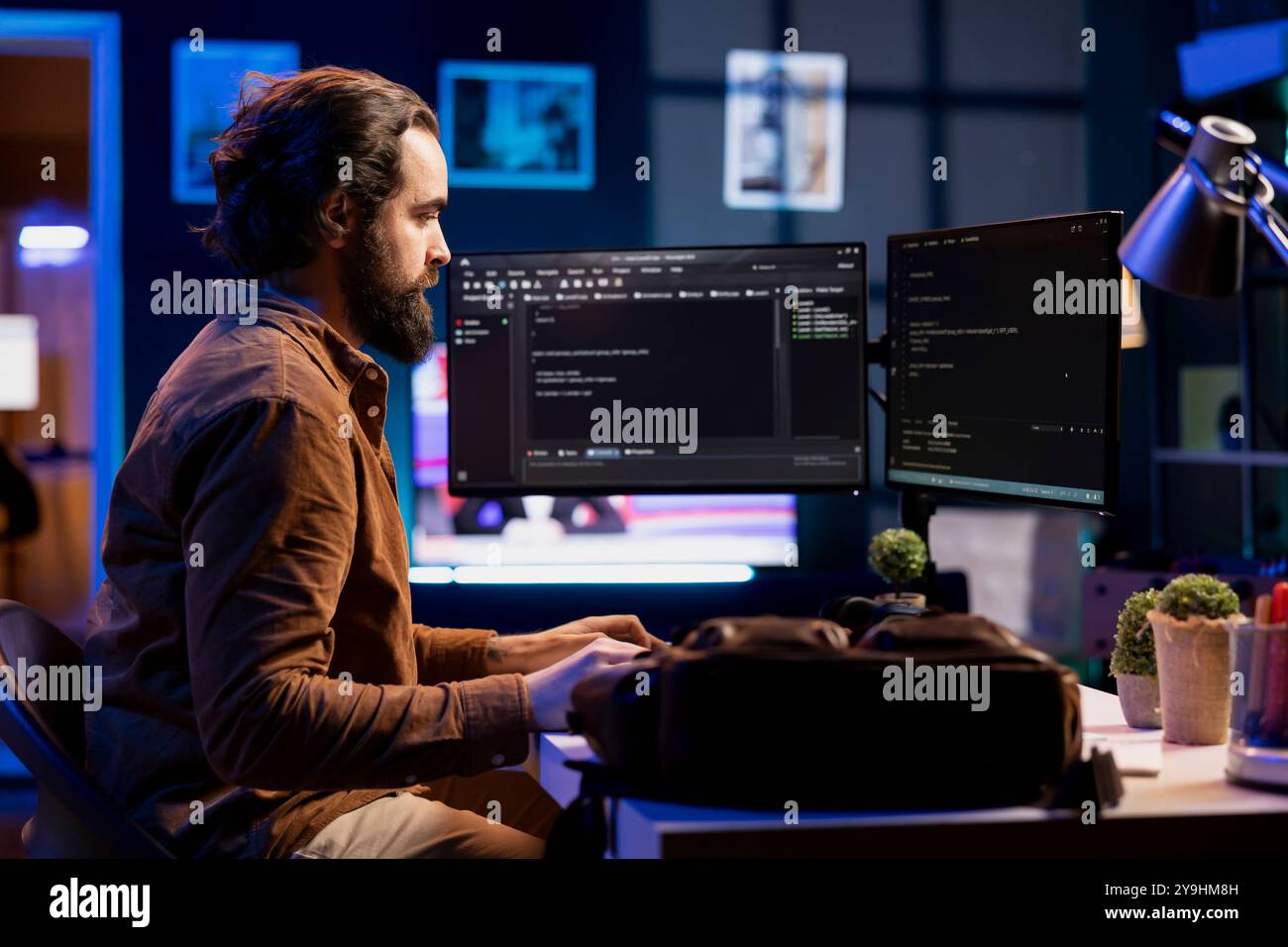 Developer in neon lit apartment implement security measures, protecting company systems and data. System administrator working from home, testing and debugging Javascript code Stock Photo