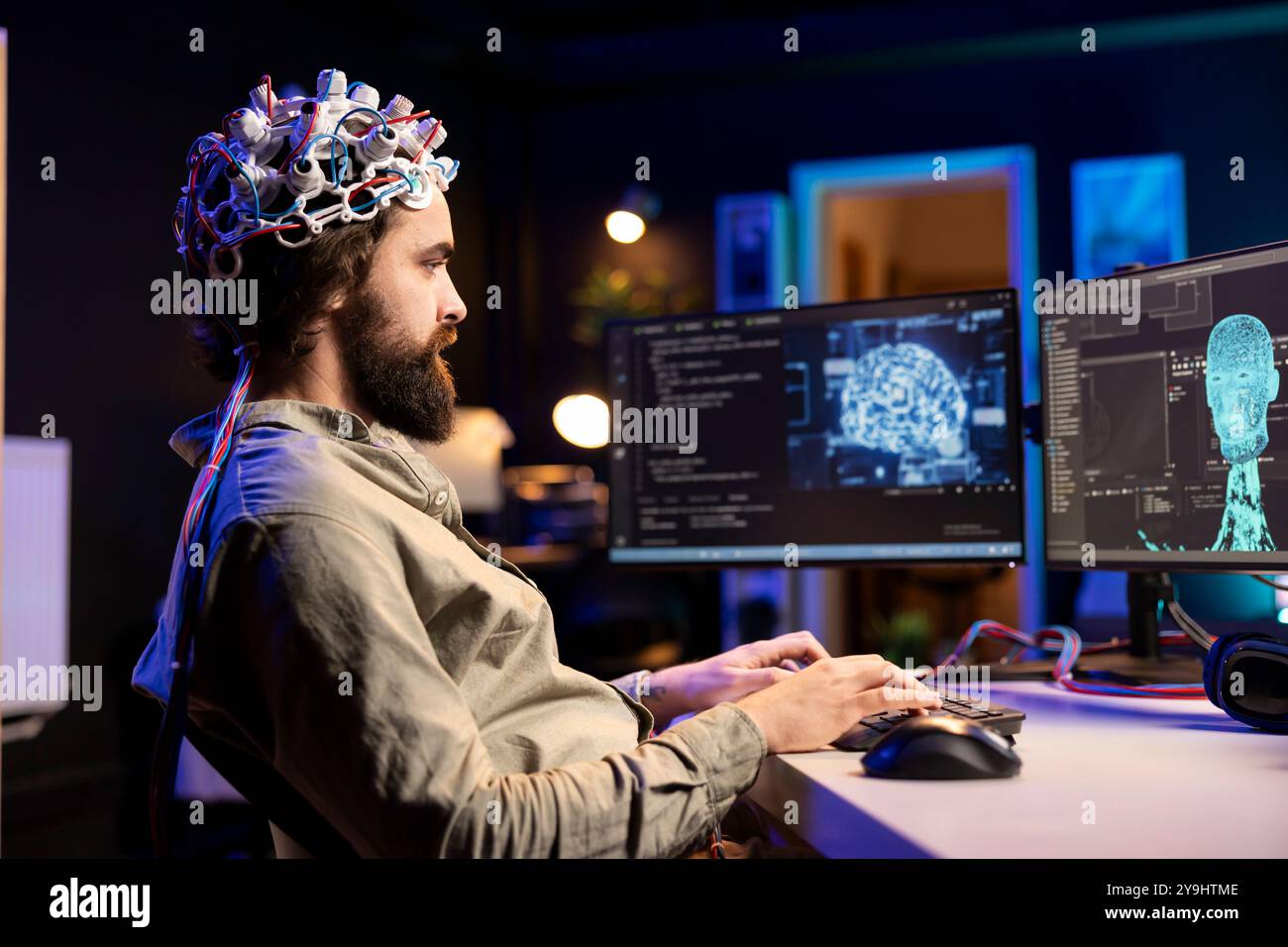 Software engineer specializing in AI using EEG headset to upload consciousness into computer. IT expert using high tech gear to create connection between brain and PC Stock Photo