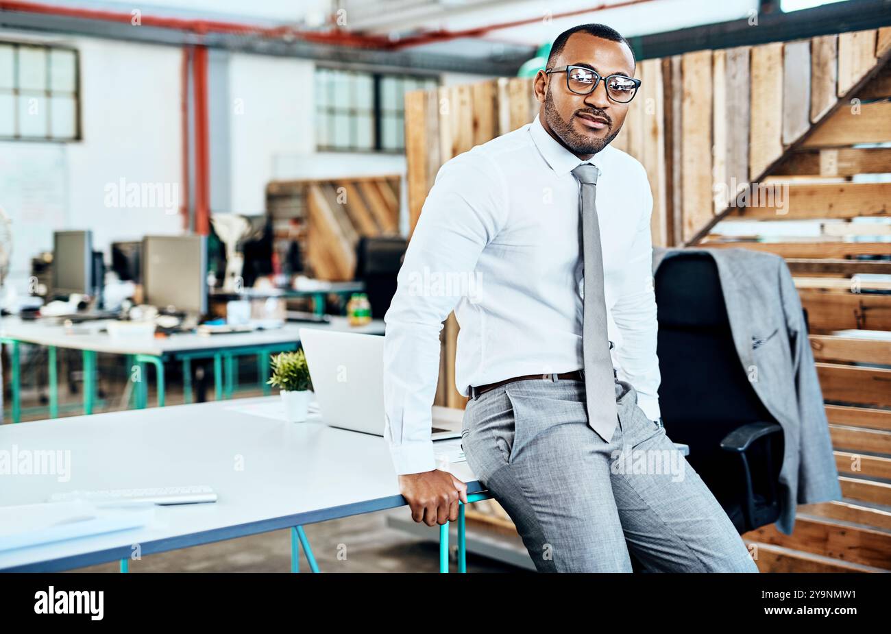 Portrait, laptop and man in office, serious and confident on desk, ideas and professional with glasses. Business, black person and lawyer of system Stock Photo