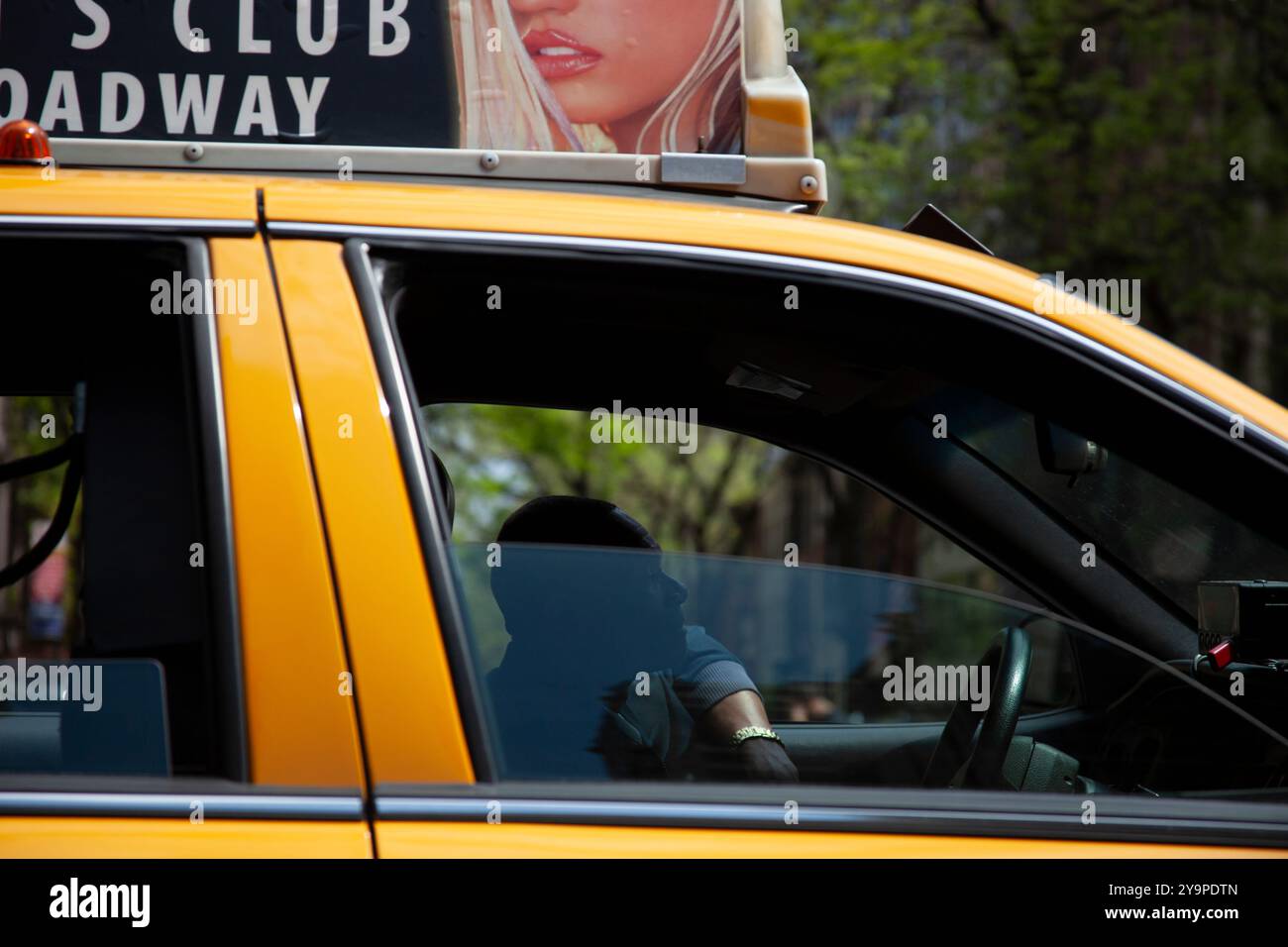 Yellow cab driver silhouetted ad with woman overhead NYC Stock Photo