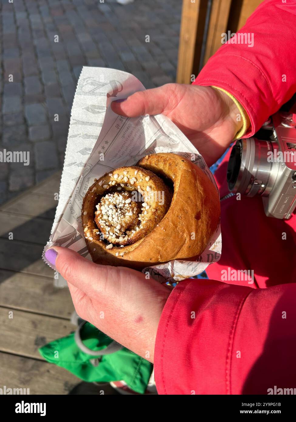 Woman holding a large cinnamon roll on International Cinnamon Roll Day in Tallinn, Estonia Stock Photo