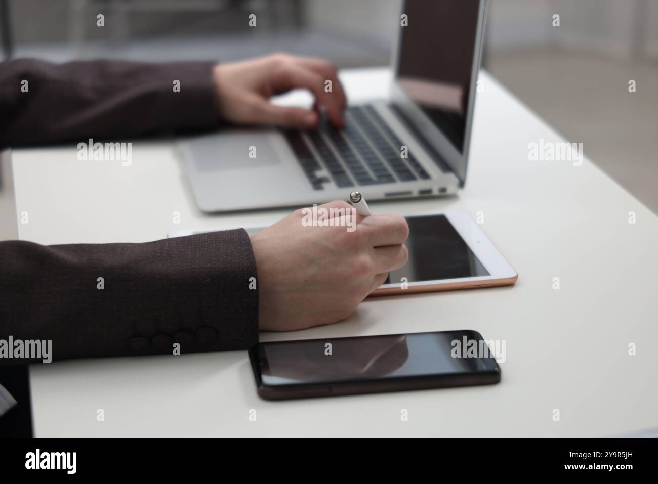 Businessman using different devices at white table indoors, closeup. Modern technology Stock Photo