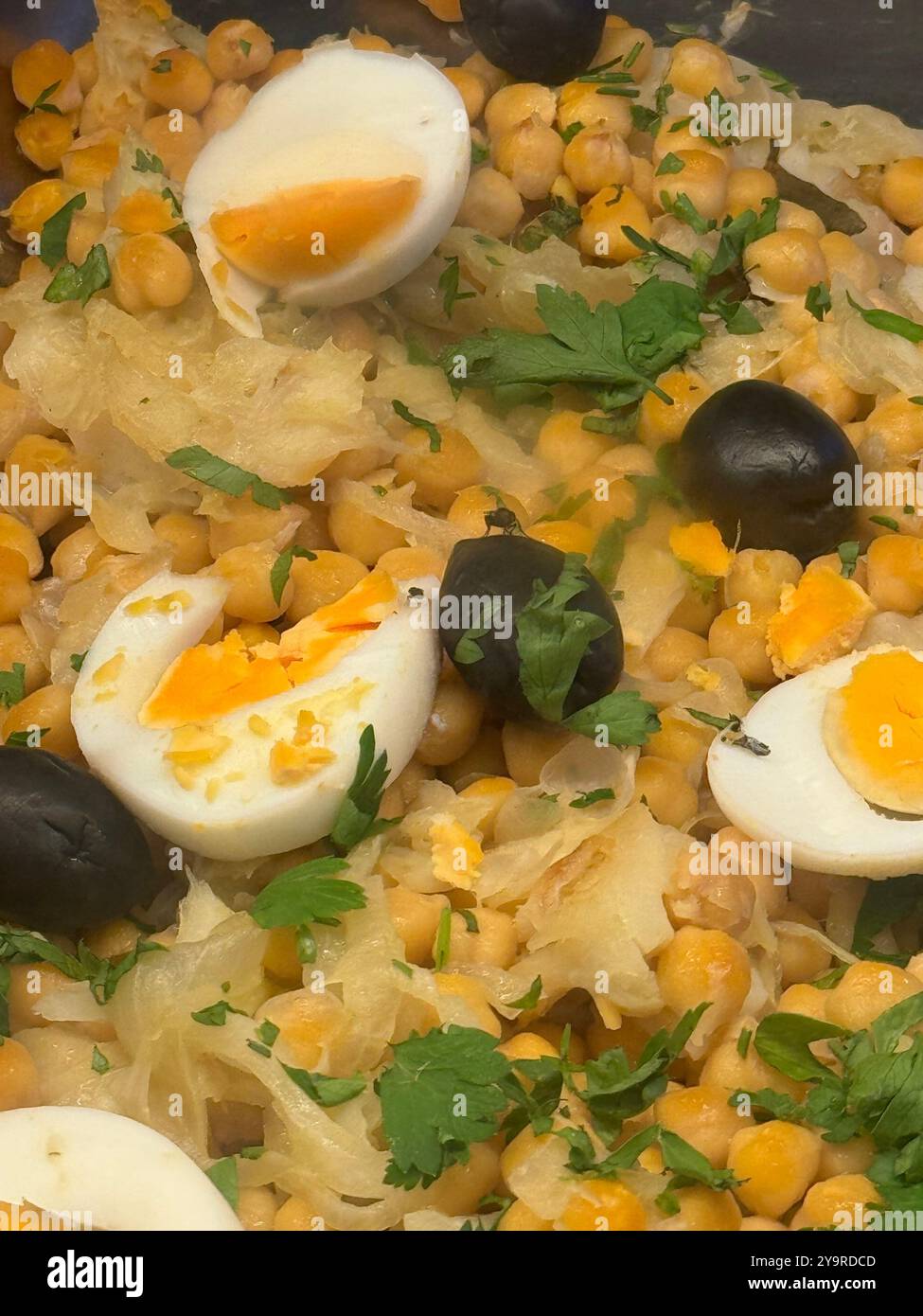 Chickpea and sauerkraut salad topped with soft‑boiled egg quarters, black olives, and fresh parsley. - Smartphone Captured Stock Image