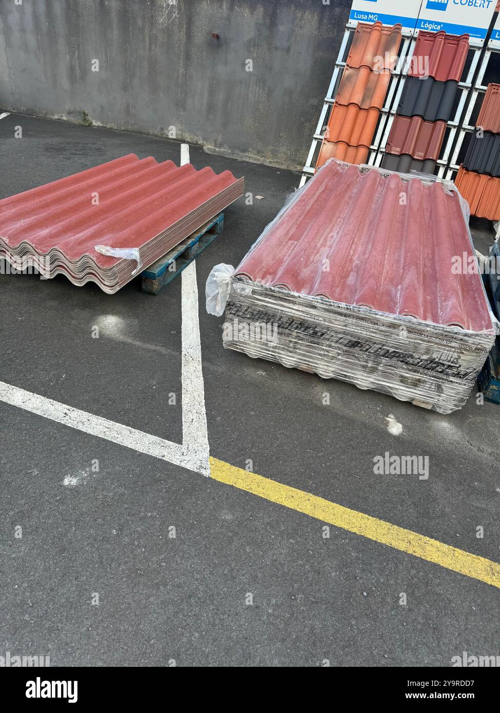 Stacks of corrugated roofing panels displayed outdoors on pallets at a building supply yard. - Smartphone Captured Stock Image