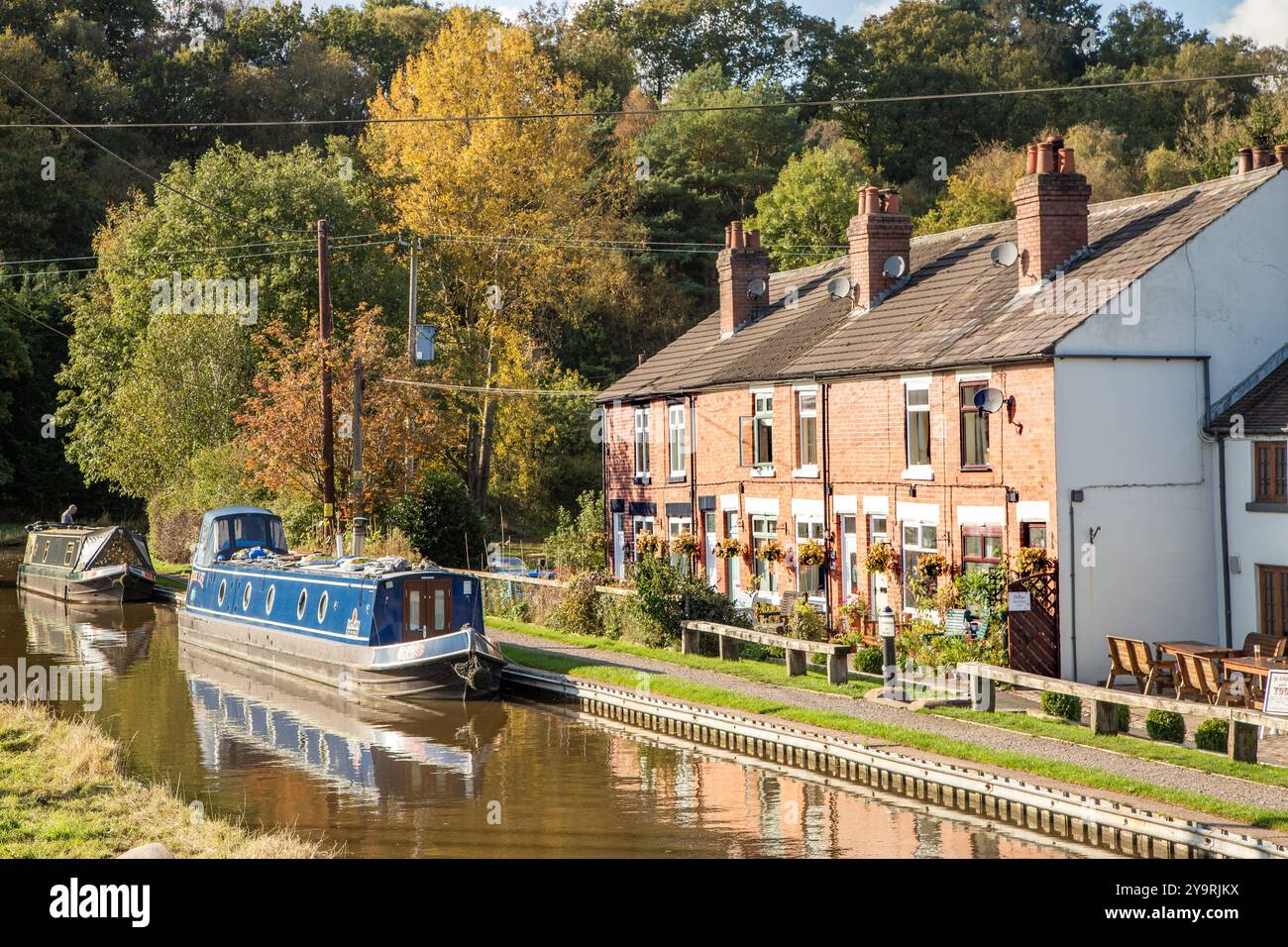 Canal narrowboats moored on the Caldon canal alongside the Hollybush cottages at Denford near Leek Staffordshire England in Autumn Stock Photo