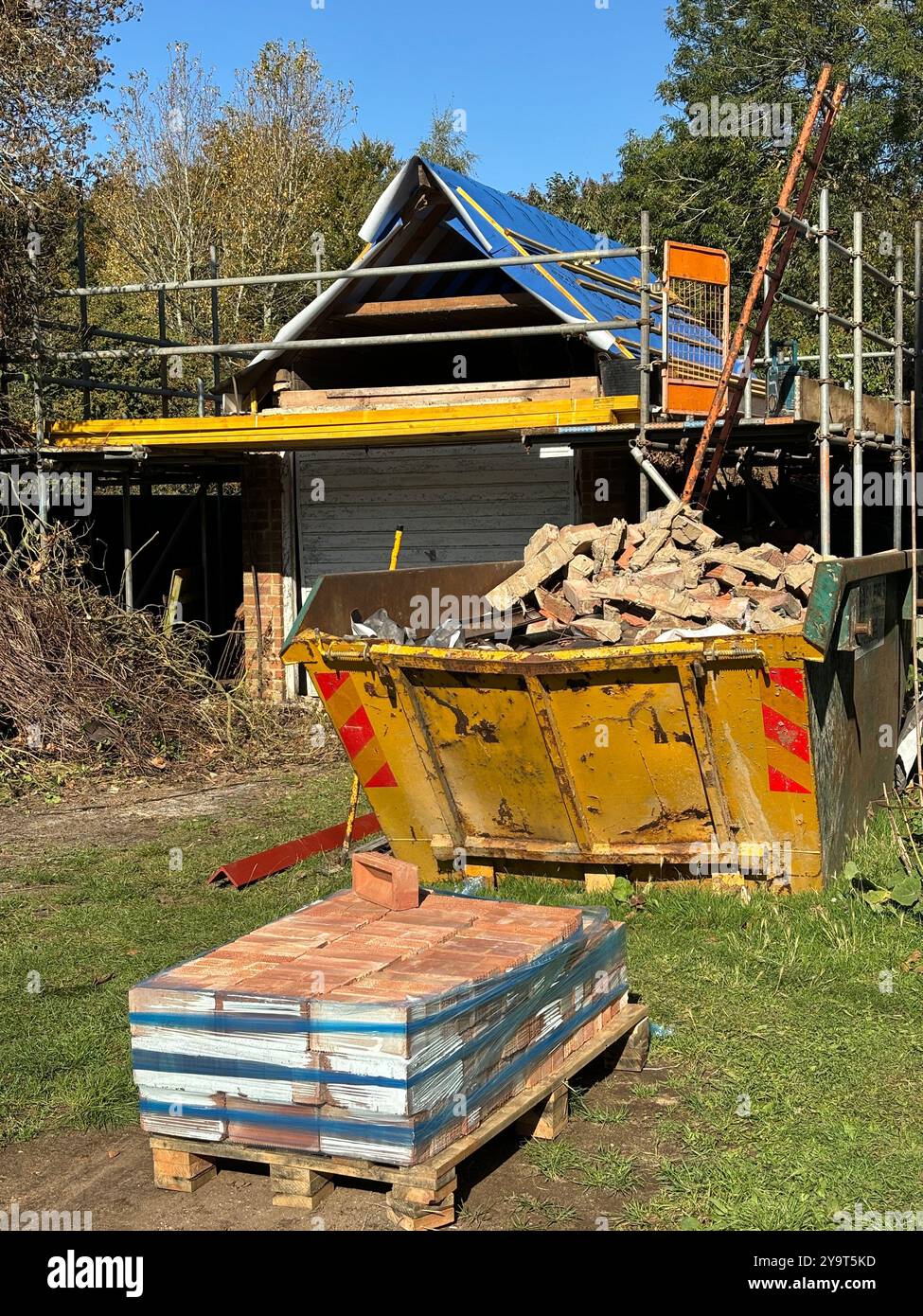 Building materials and refuse skip for waste rebuilding garage roof, UK ...