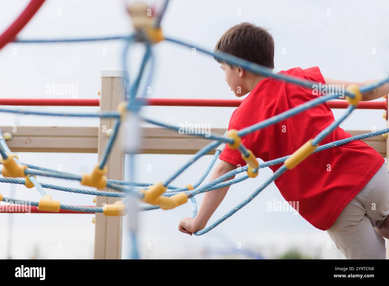 Happy boy playing and hanging on ropes on playground. Children's ...