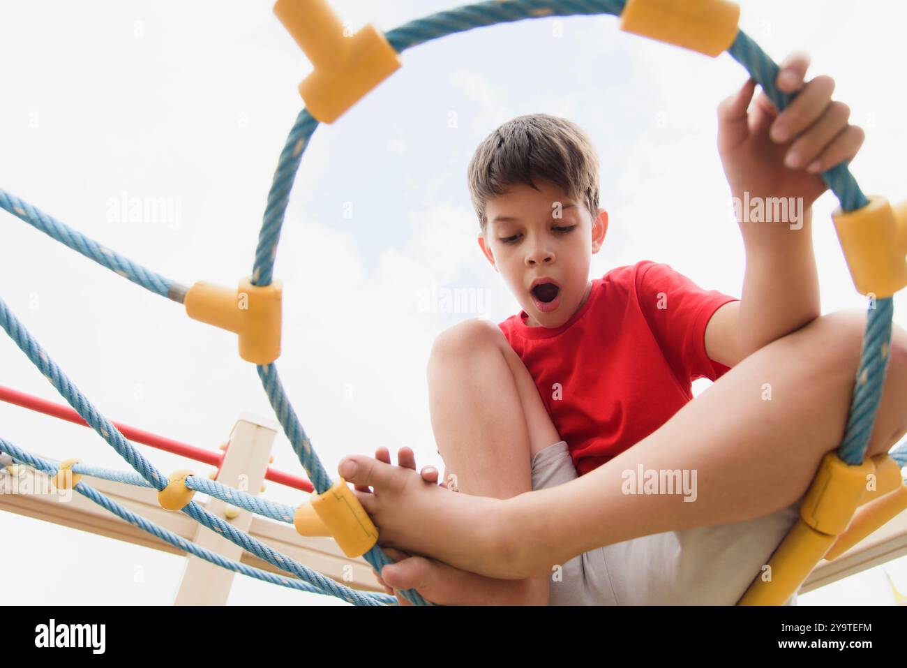 Happy boy playing and hanging on ropes on playground. Children's ...