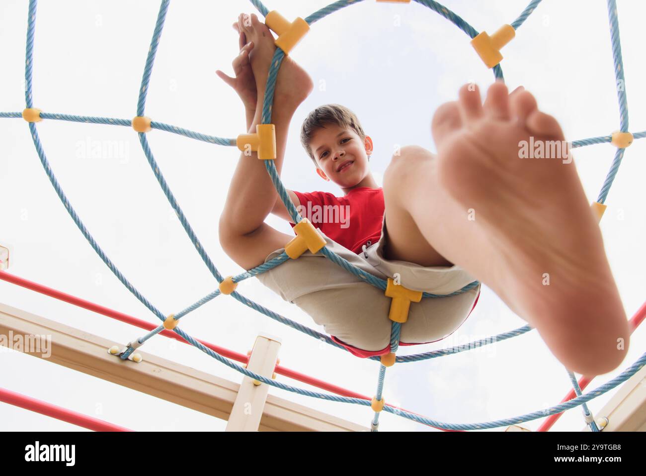 Happy boy playing and hanging on ropes on playground. Children's ...