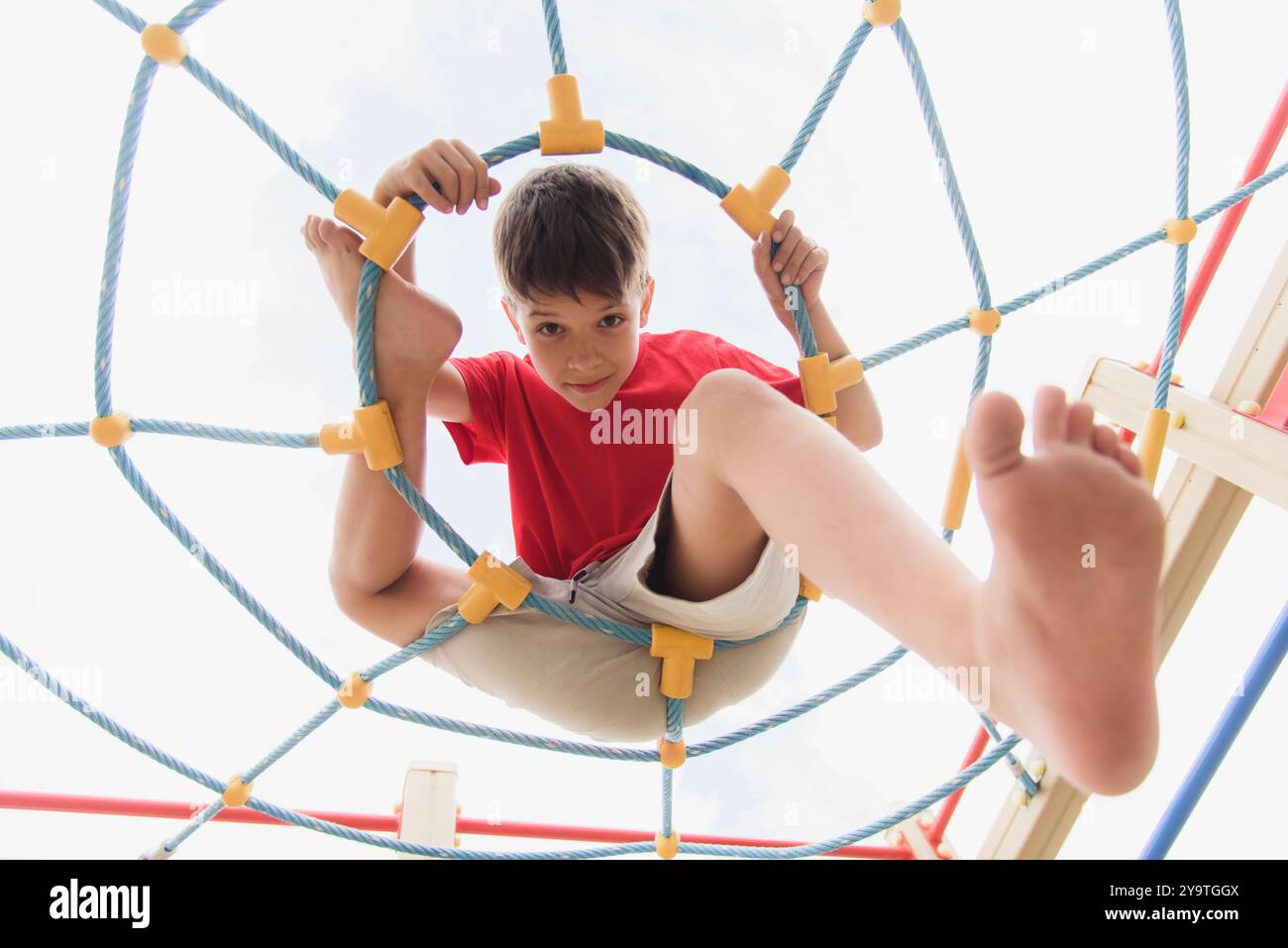 Happy boy playing and hanging on ropes on playground. Children's ...