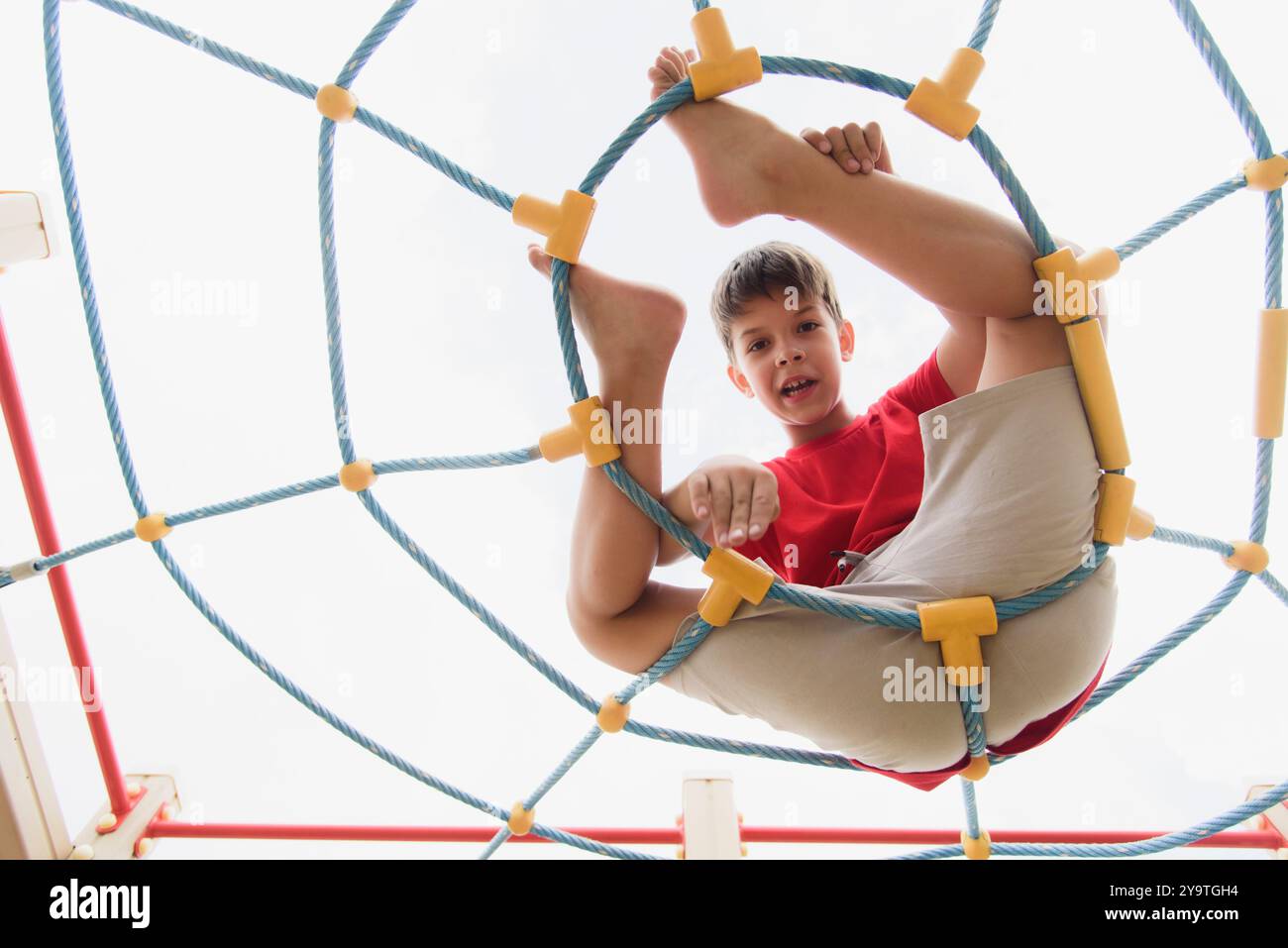 Happy boy playing and hanging on ropes on playground. Children's ...