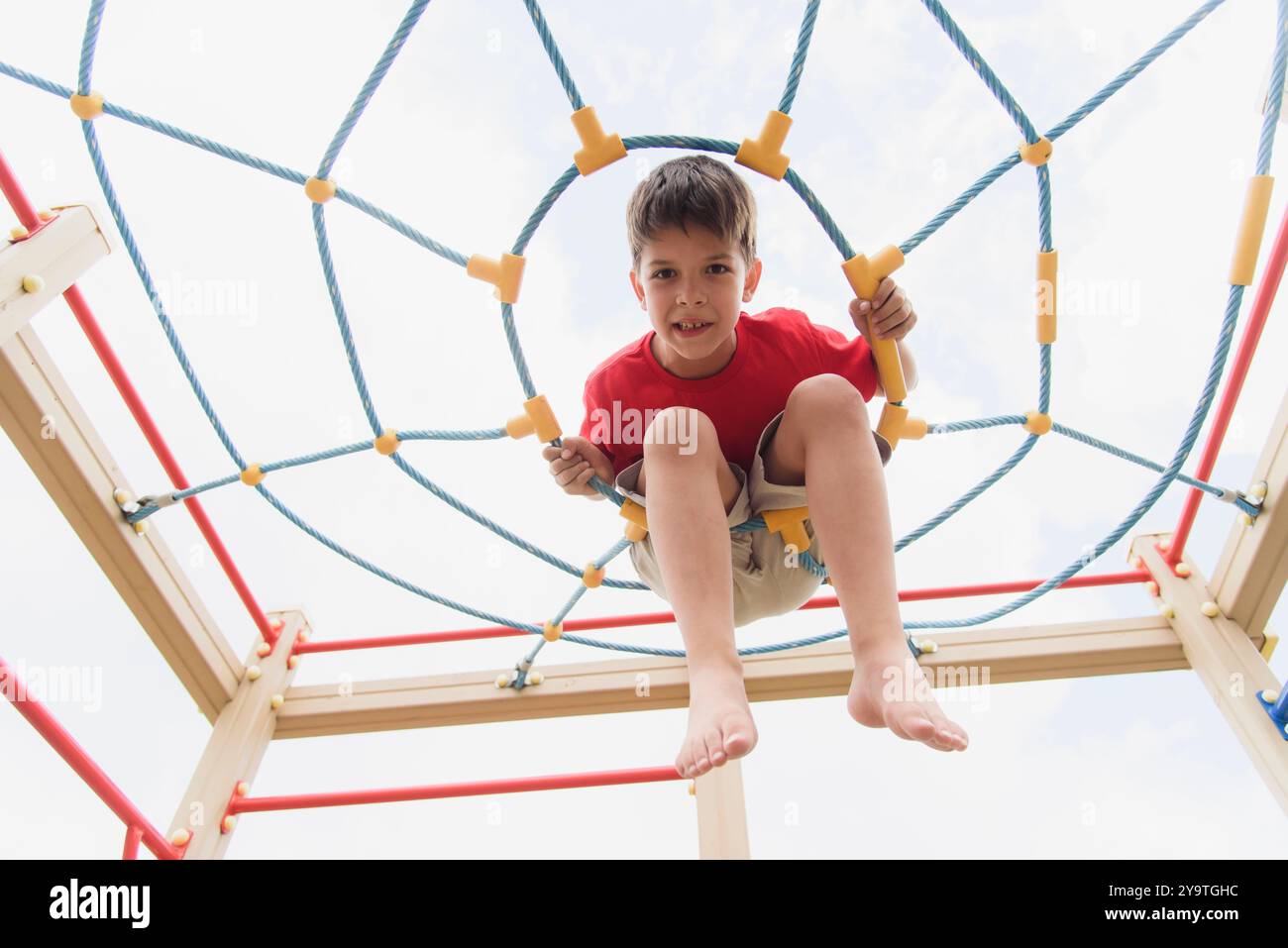 Happy boy playing and hanging on ropes on playground. Children's ...