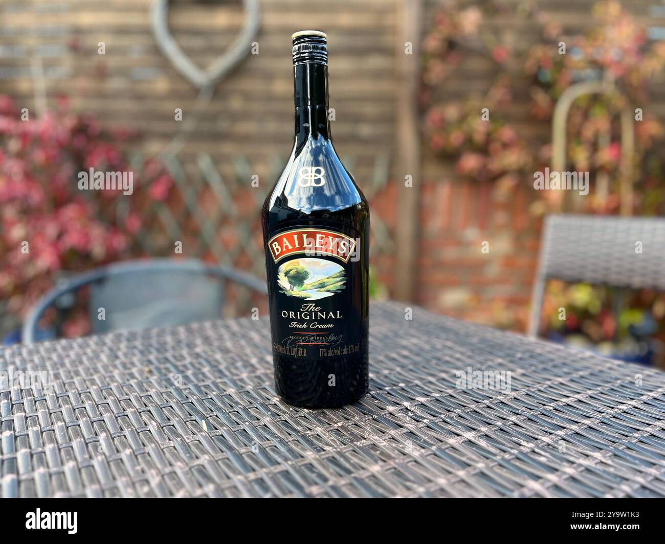 A bottle of Baileys Irish Cream on a garden table. - Smartphone Captured Stock Image