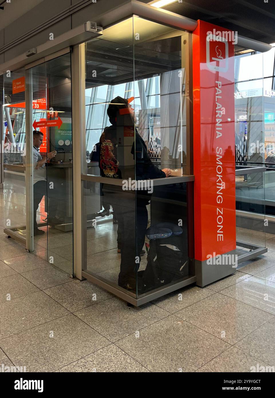 Airport smoking area zone indoor designated glass booth at Warsaw Chopin Airport, Poland, EU - Smartphone Captured Stock Image
