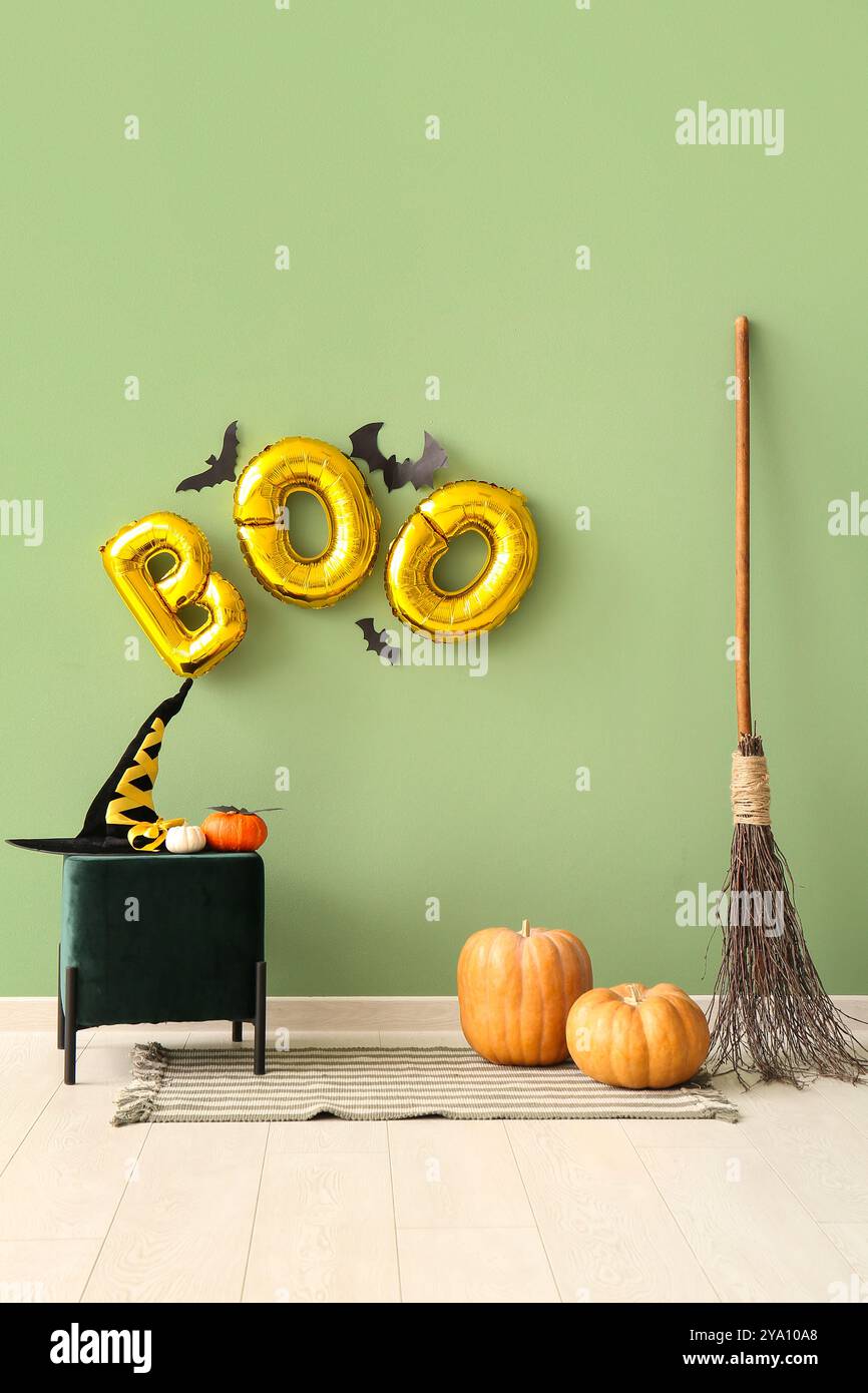 Word BOO made of balloons with paper bats on green wall in room interior Stock Photo