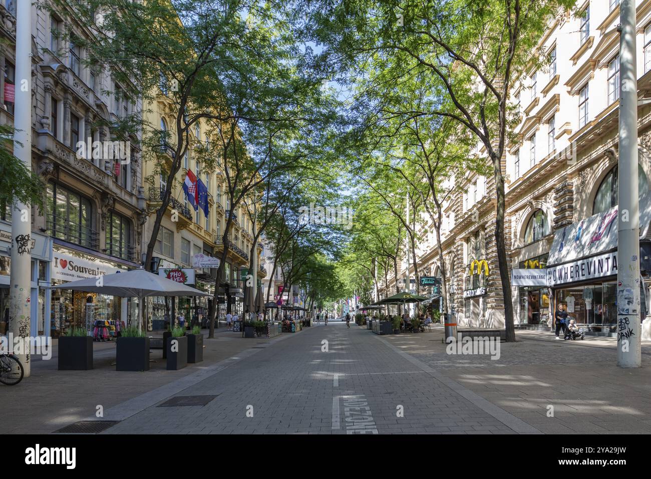 Lively shopping street in summer, lined with trees and numerous shops, Vienna Stock Photo