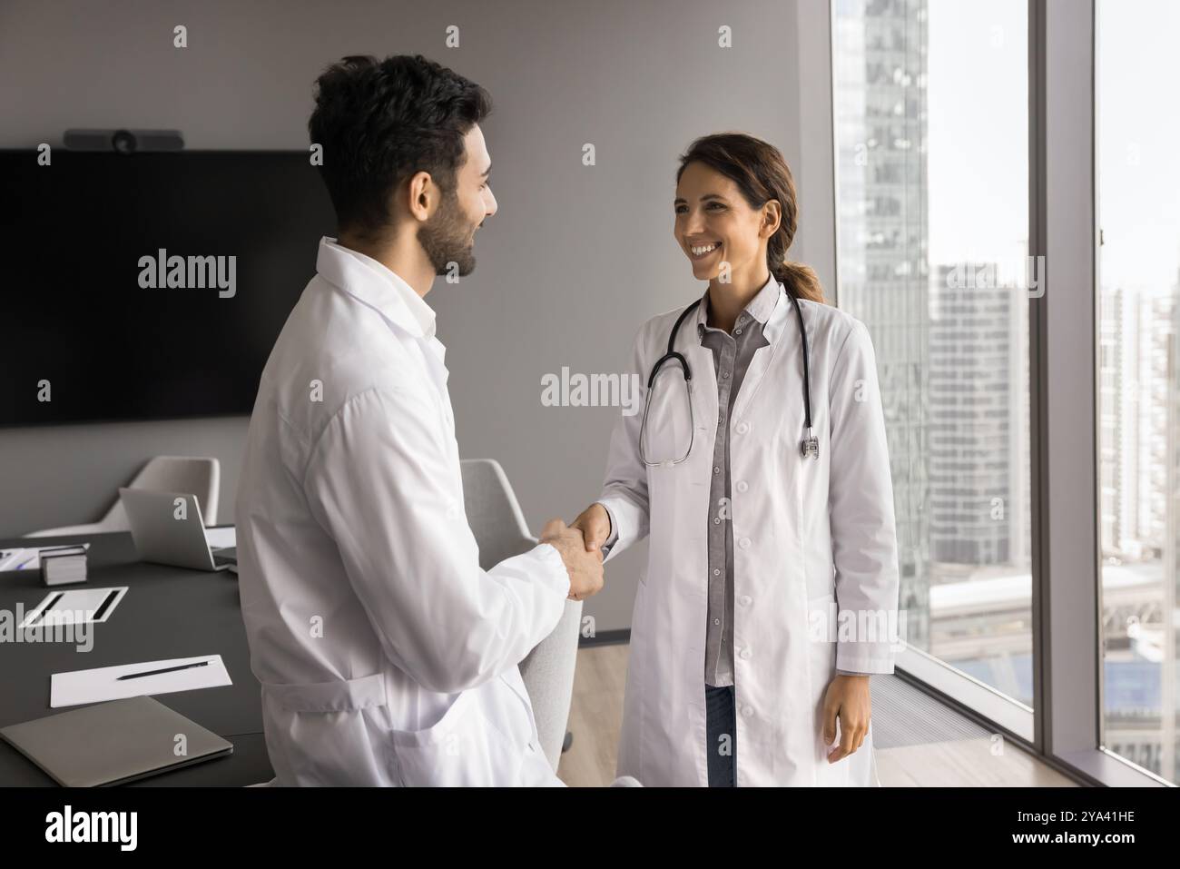 Young man woman medics coworkers shake hands after successful partnership Stock Photo