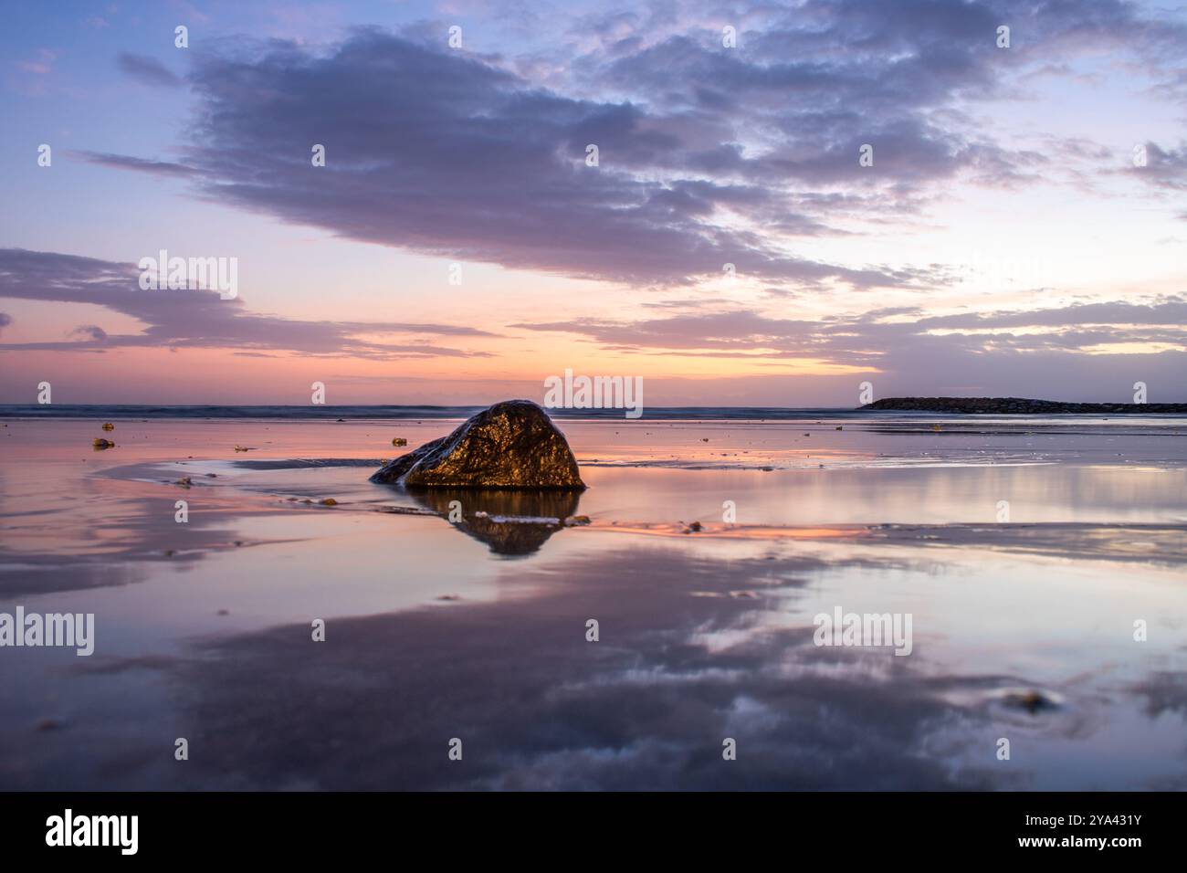 Water landscape, gently sloping sandy beach with light waves. The incredible sky is reflected in the wet sand in the romantic sunset in Kuta, Bali Stock Photo