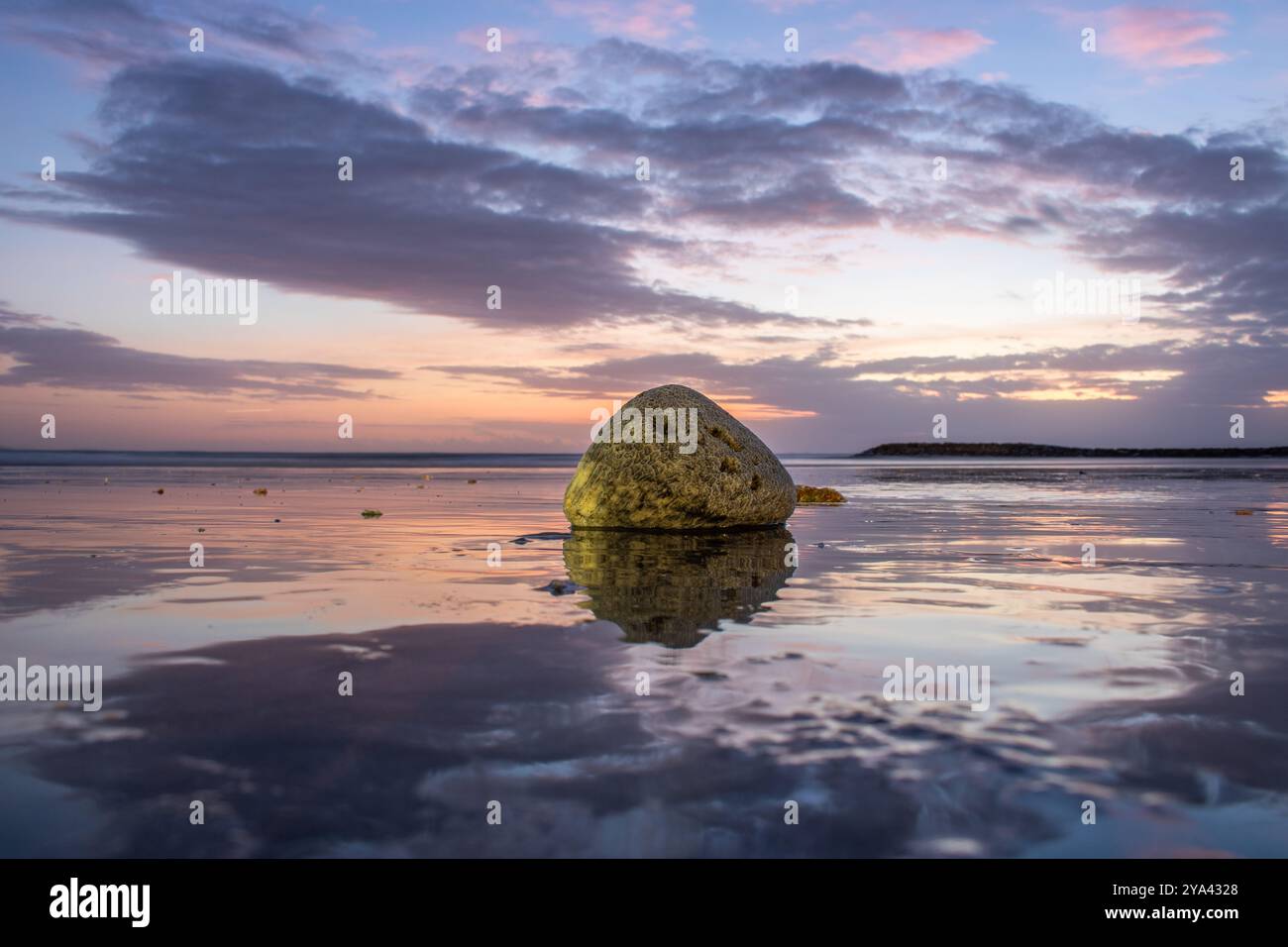 Water landscape, gently sloping sandy beach with light waves. The incredible sky is reflected in the wet sand in the romantic sunset in Kuta, Bali Stock Photo