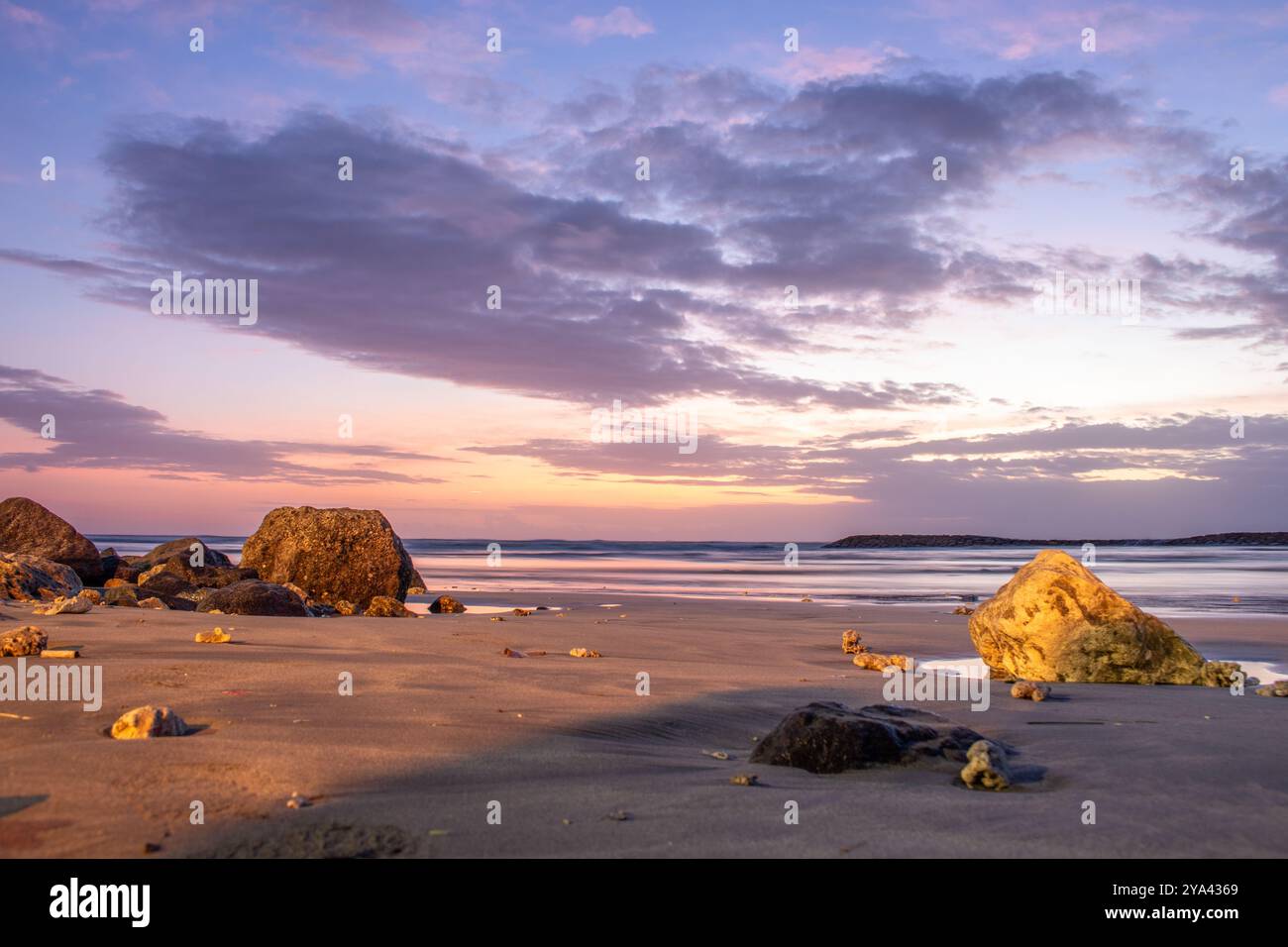 Water landscape, gently sloping sandy beach with light waves. The incredible sky is reflected in the wet sand in the romantic sunset in Kuta, Bali Stock Photo