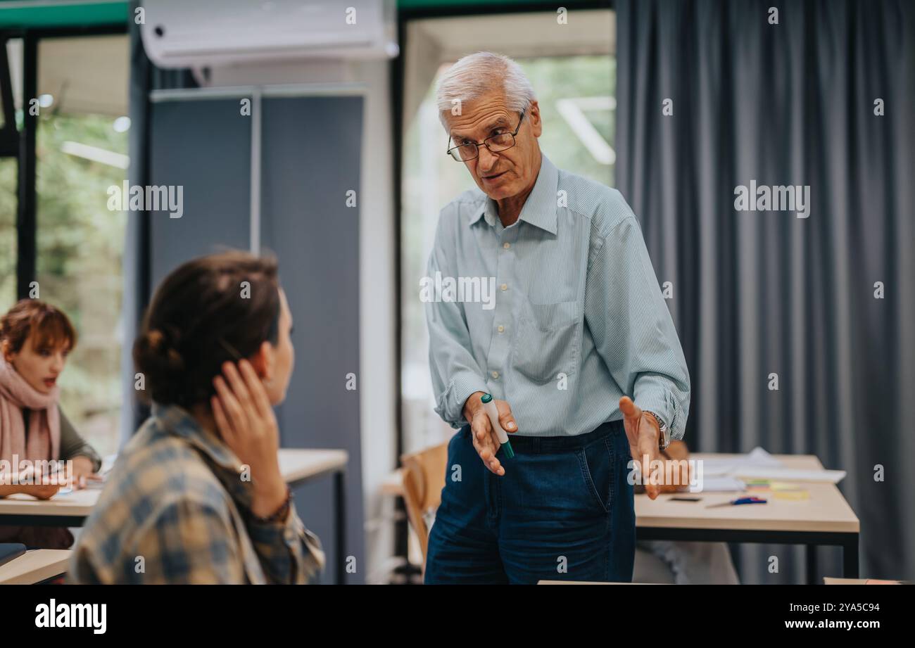 Elderly professor engaging with students in classroom setting Stock Photo