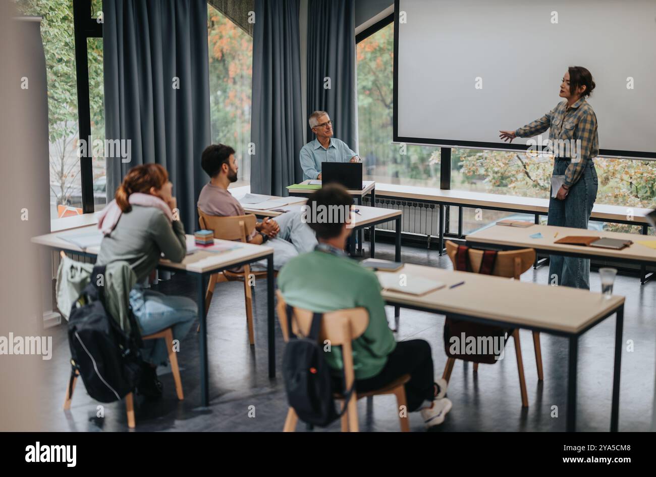 Students in classroom engaging with elderly professor during a lesson Stock Photo