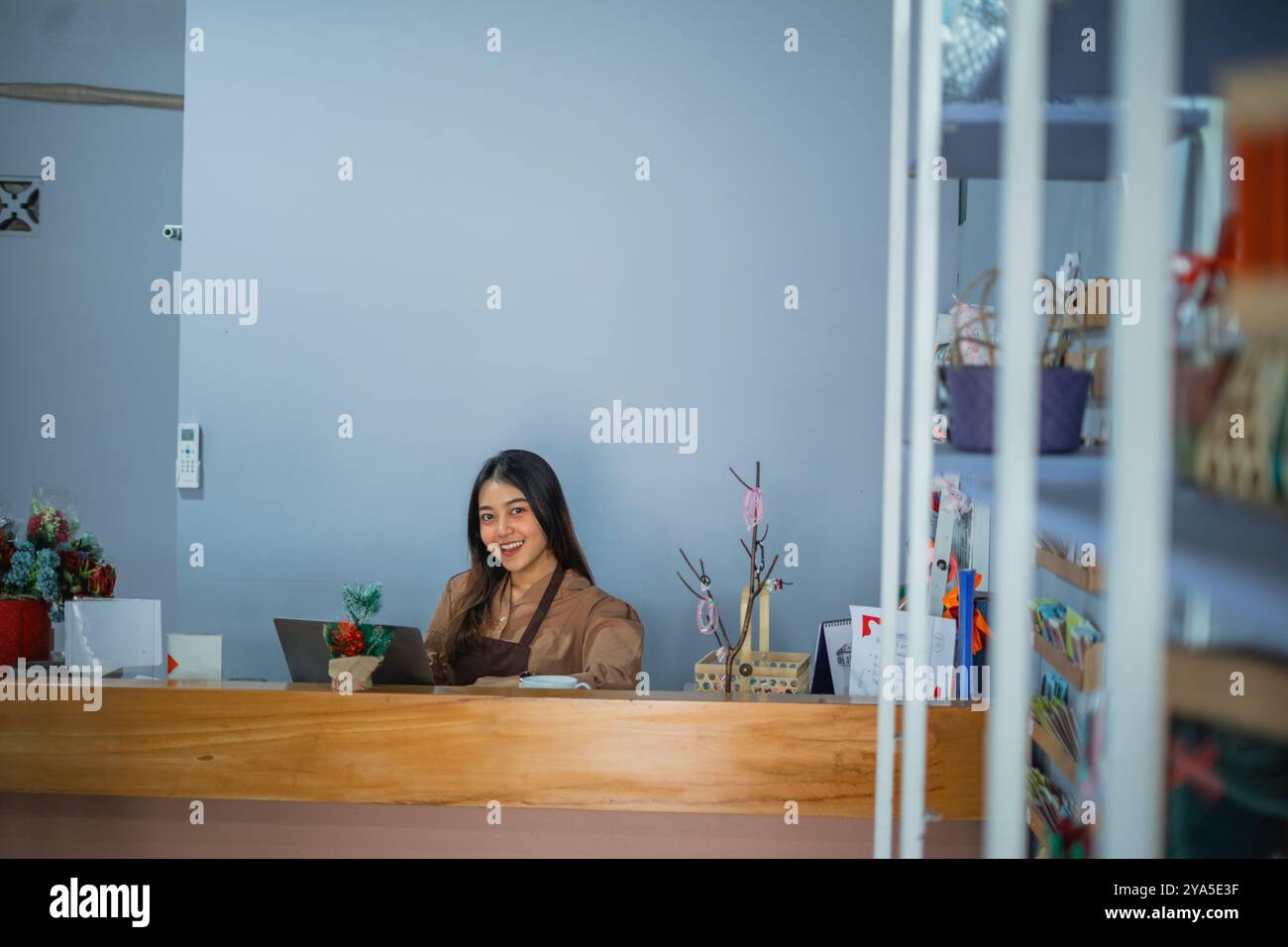 Asian girl smiling shopkeeper behind the counter of a souvenir shop ...