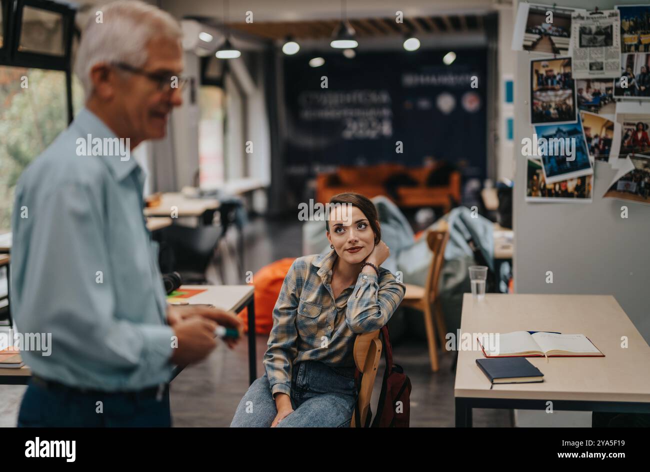 Students engaging with elderly professor in a modern classroom setting Stock Photo